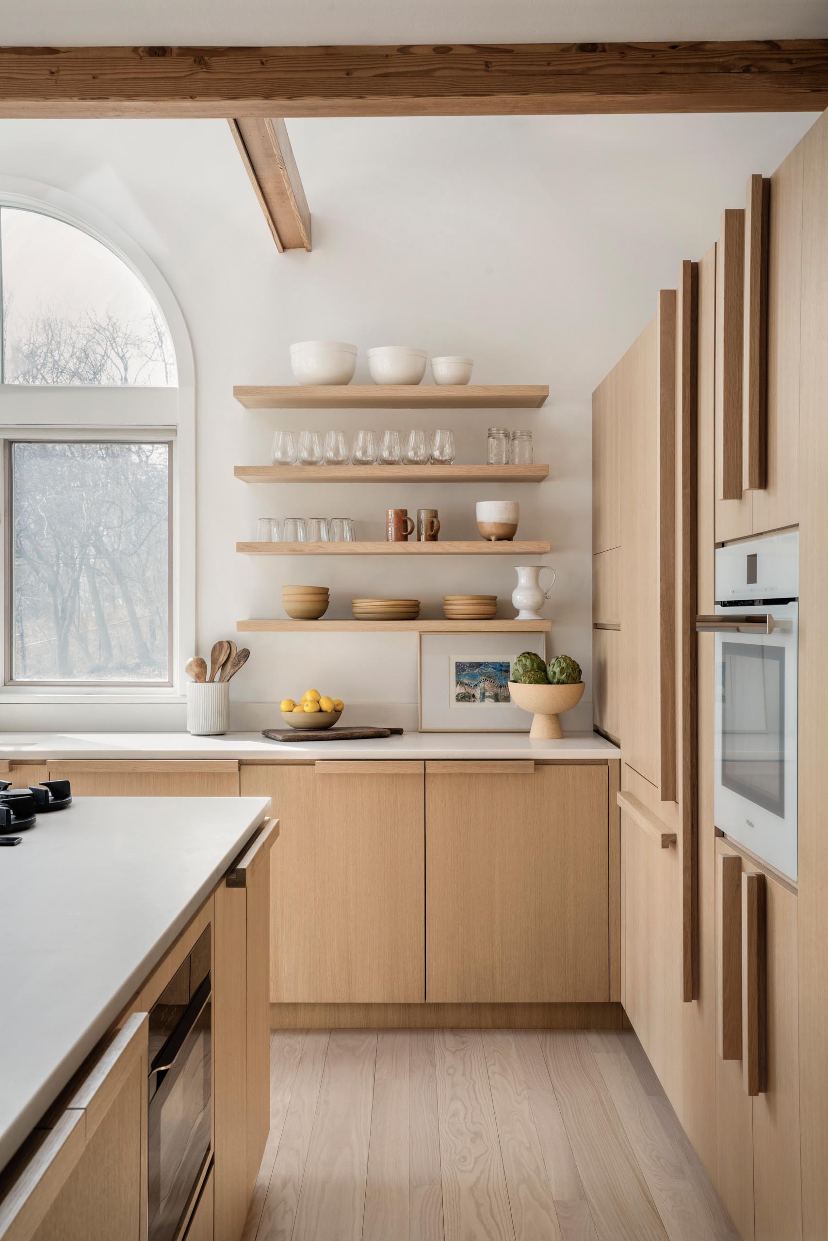A remodeled kitchen with water-based white rift oak for the cabinets, open shelving, a large island, and quartz countertops.