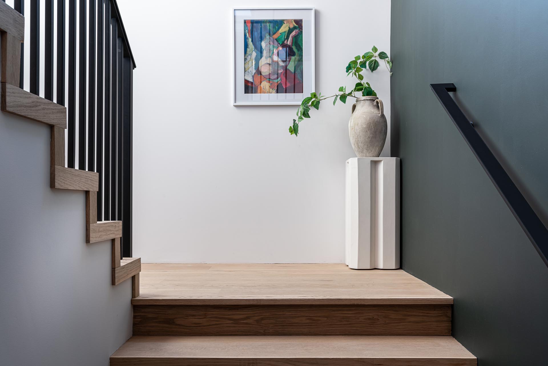 Wood stairs with a black handrail lead to the upper floor of this modern farmhouse inspired home.