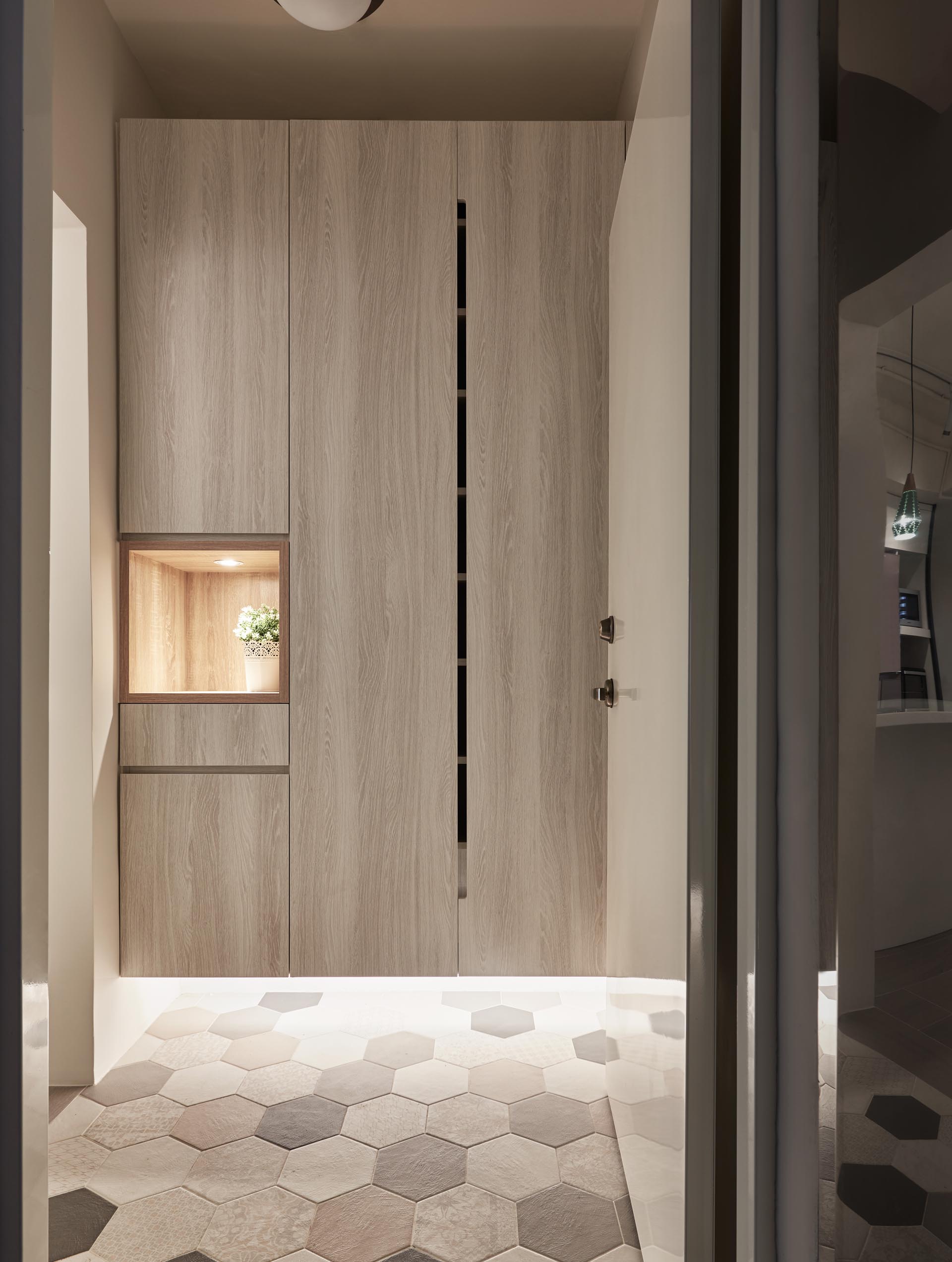 The entryway has tall storage closets that float above a tiled floor, that's highlighted with the use of hidden LED lights. A small open shelf with a light is an ideal place for keys and wallets.