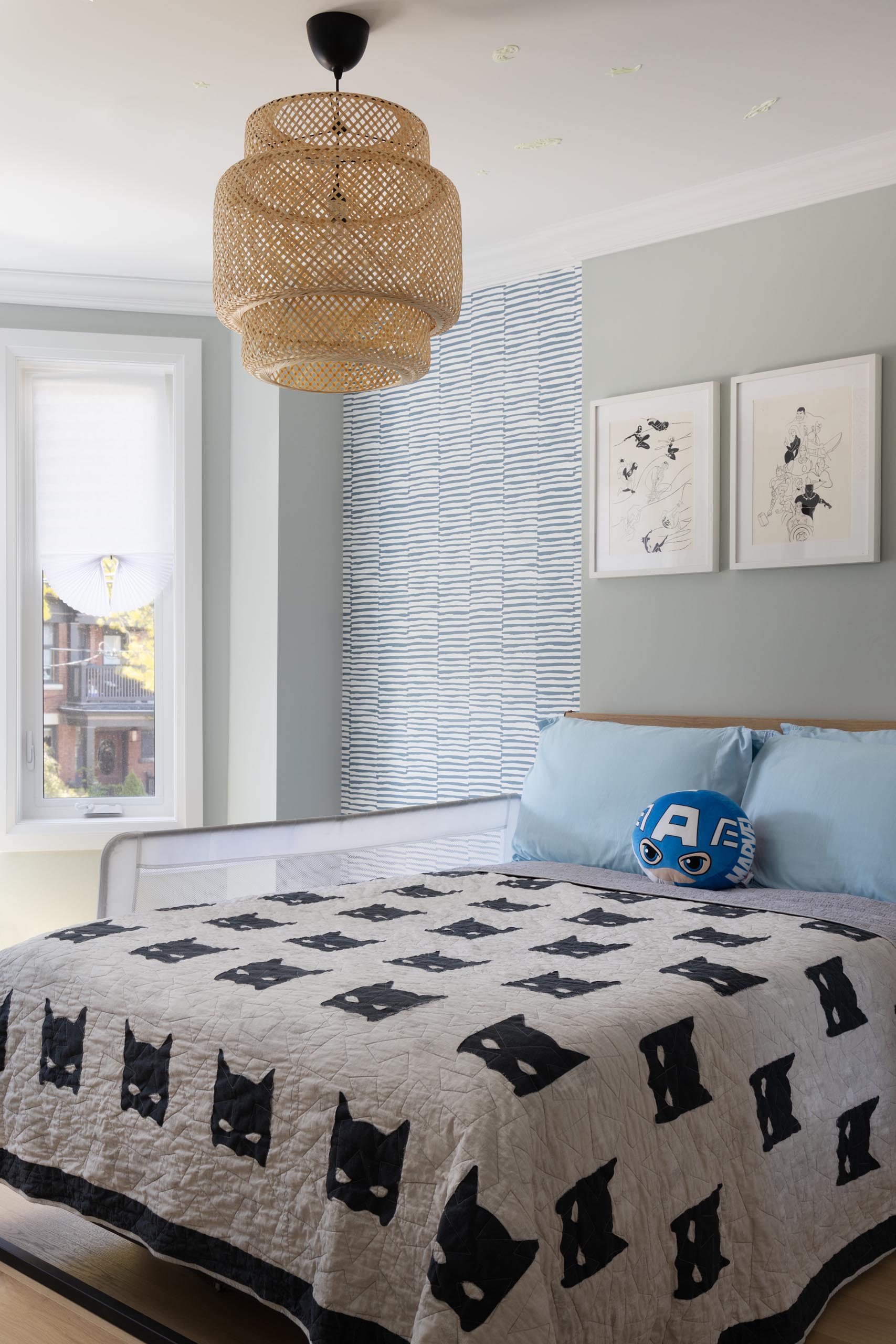 In this contemporary bedroom, there's a woven light fixture, patterned wallpaper, and artwork.