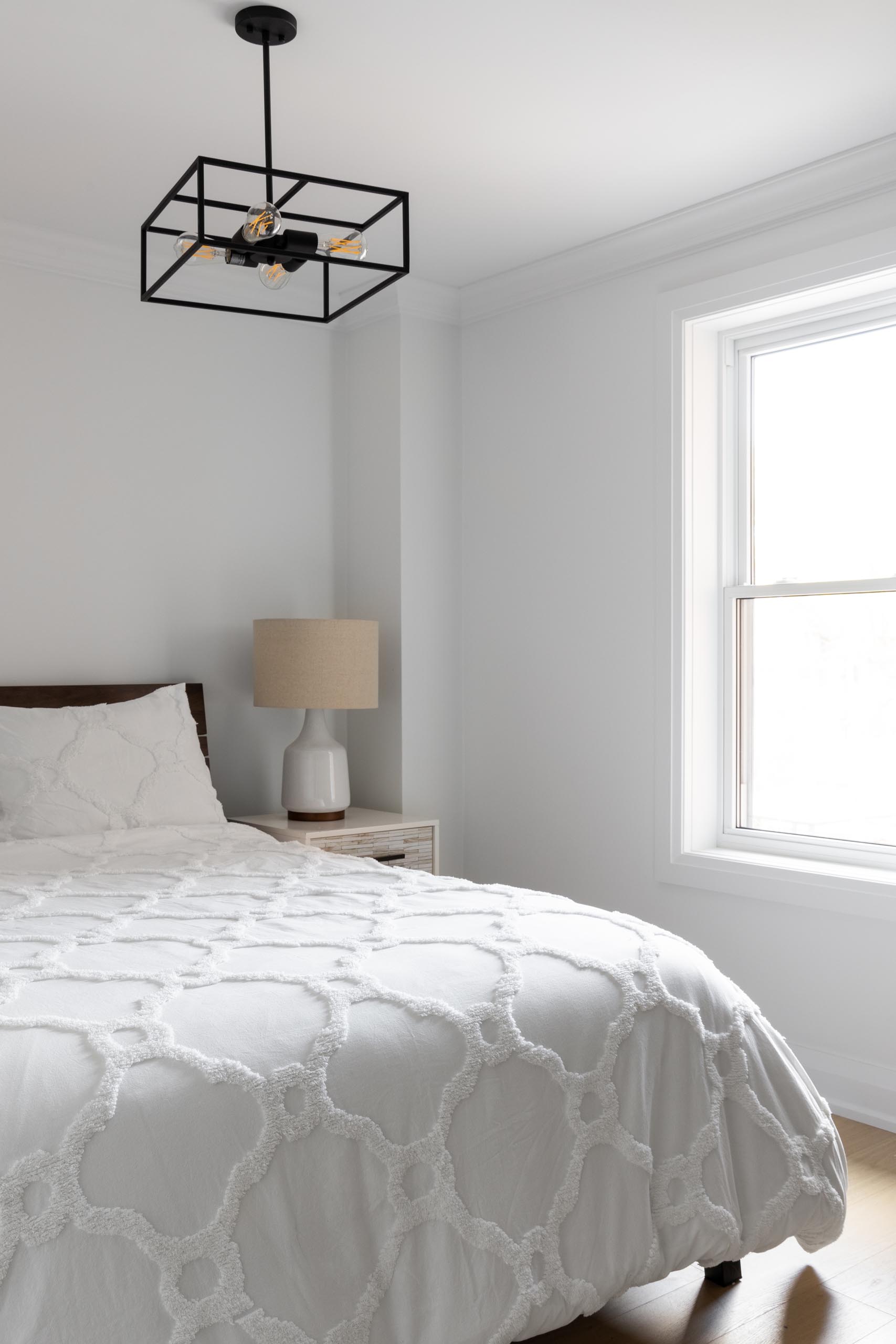 A simple contemporary bedroom design with a minimalist black light fixture that draws the eye upwards to the ceiling.