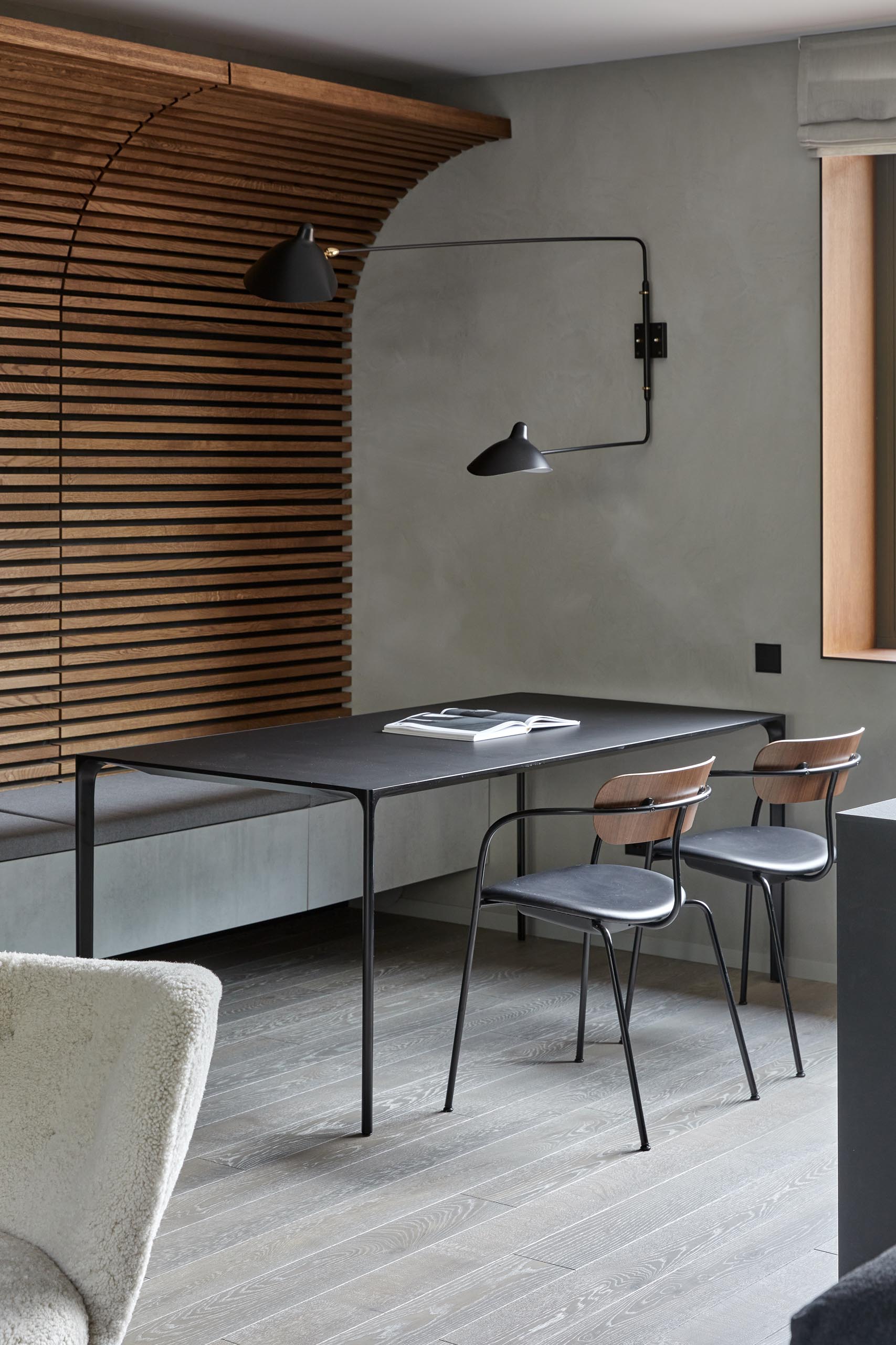 In this modern dining area, the bottom of the wood wall meets a ledge with an upholstered cushion that doubles as bench seating for the dining table.