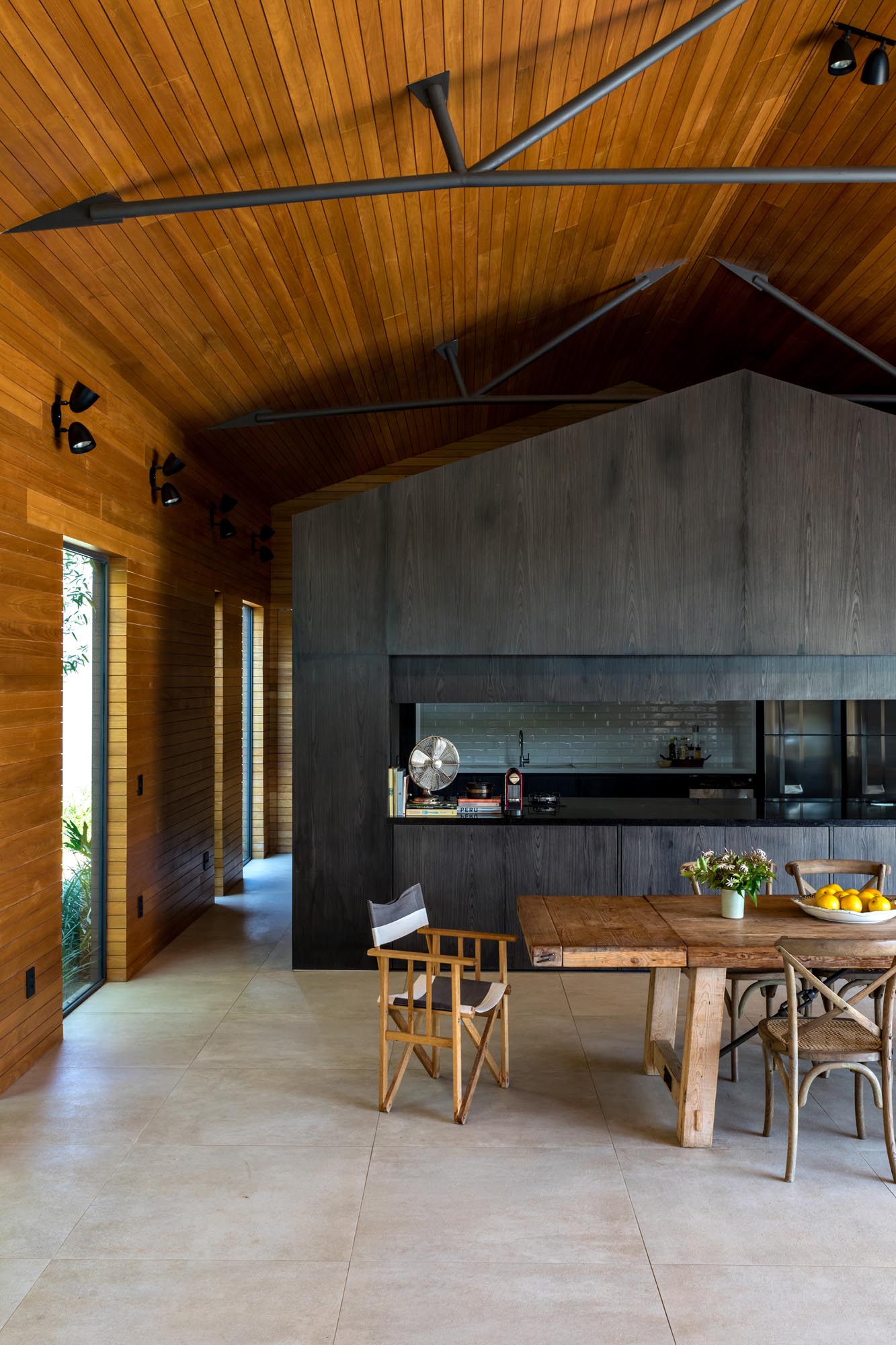 The interior of this modern home is lined in Tauari, a Brazilian pale wood, while the kitchen is completely made out of darkened wood. The kitchen can also be hidden from view, as a section of the cabinetry can be lowered down to close it off.