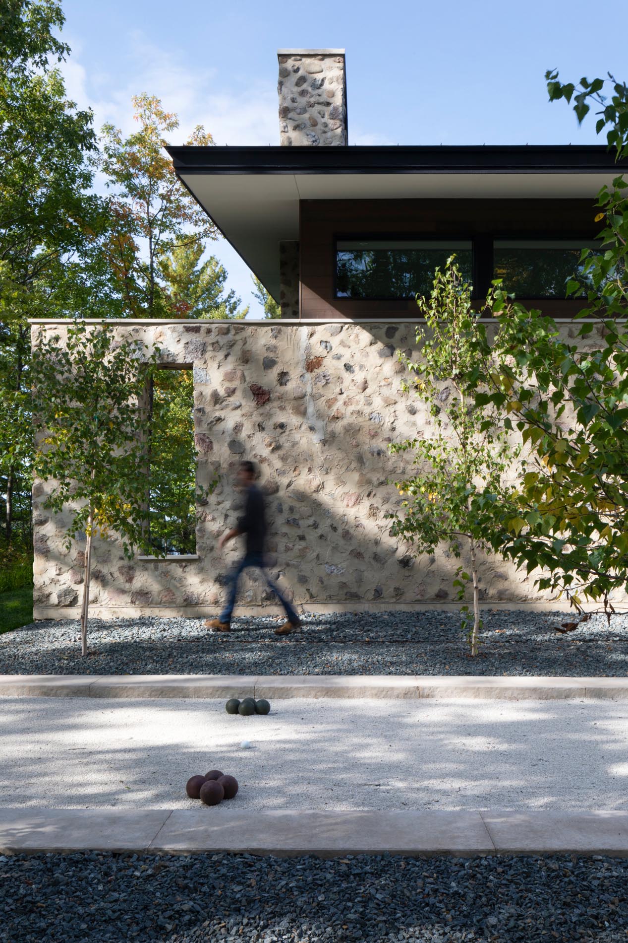 A modern home with stone walls and a bocce court.