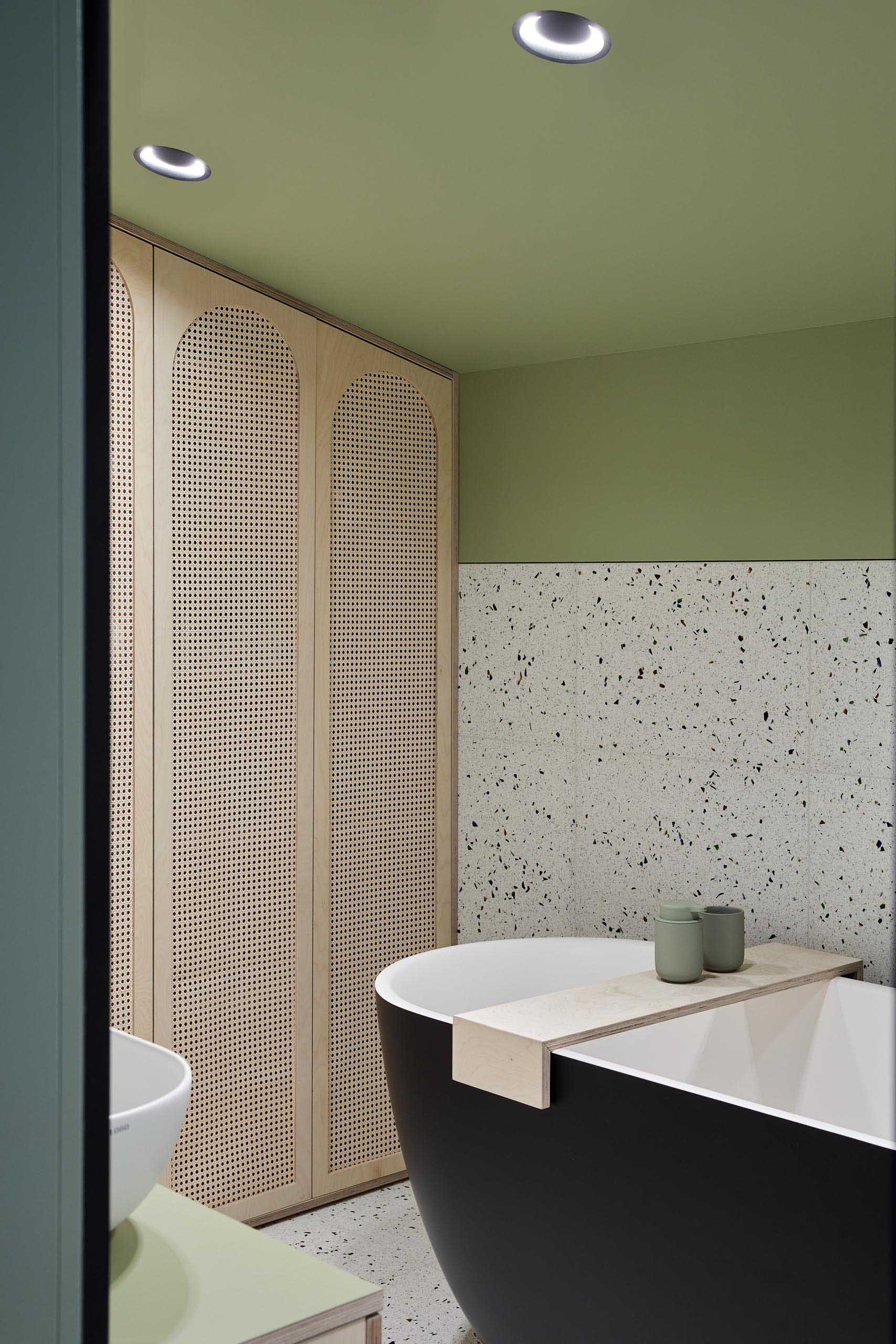 In this modern bathroom, matte green walls have been combined with terrazzo and wood pendant lights.