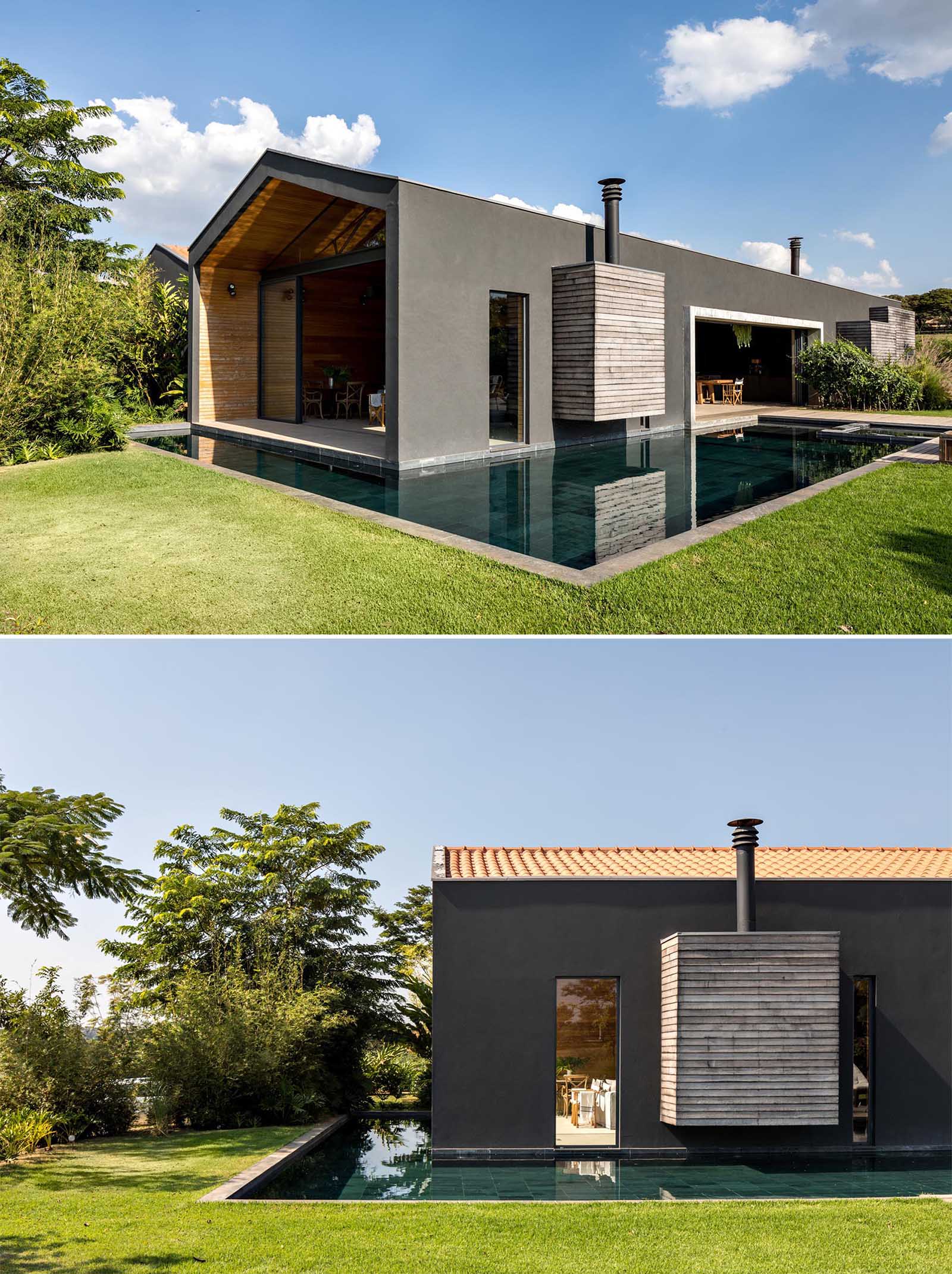The exterior of this modern home is a black-painted mass, contrasting the surrounding nature, and providing a bold backdrop for the outdoors spaces, like the patio and swimming pool.