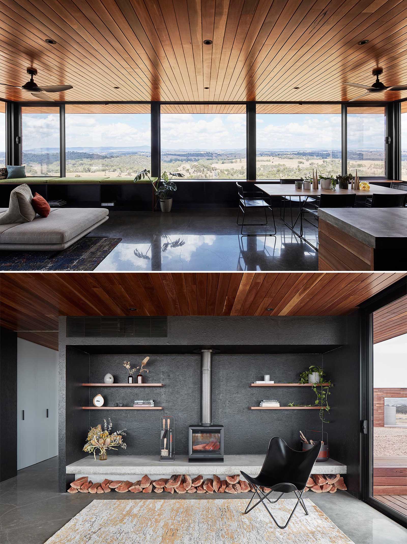 The living space of this small house, has a wood ceiling and large windows, and is open plan with a dining area and kitchen, while the living room includes black accent wall with a fireplace, and a window bench.