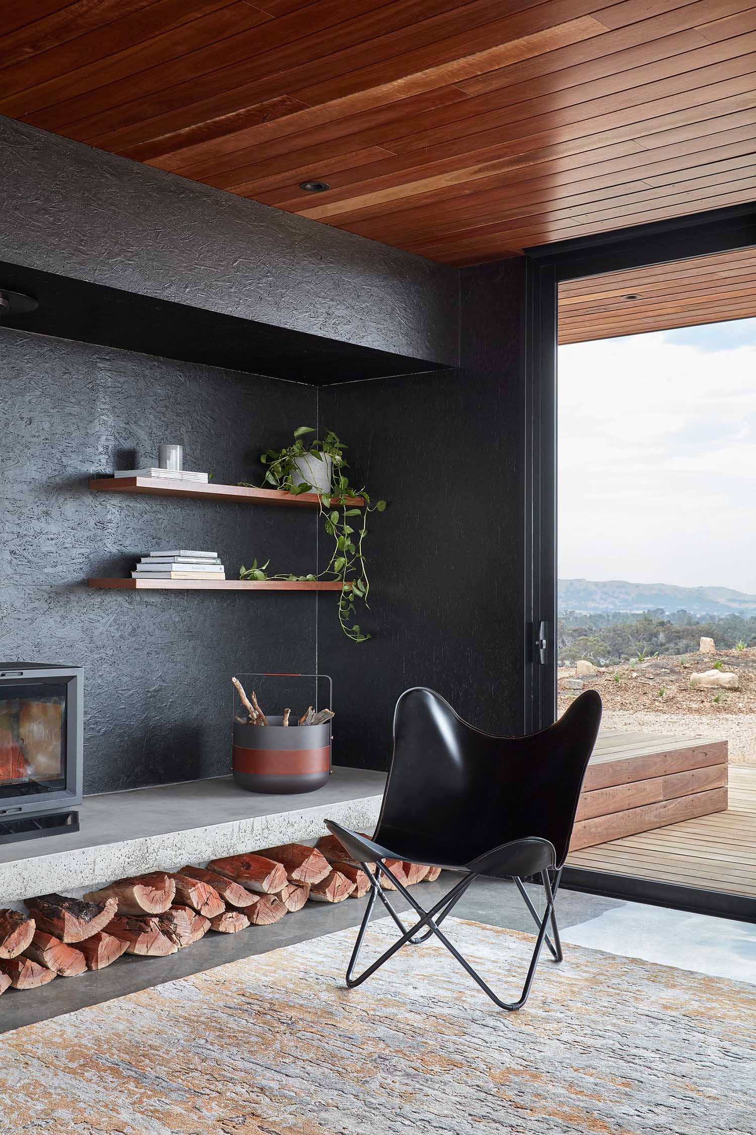 A black accent wall is the backdrop of a fireplace and floating wood shelves.