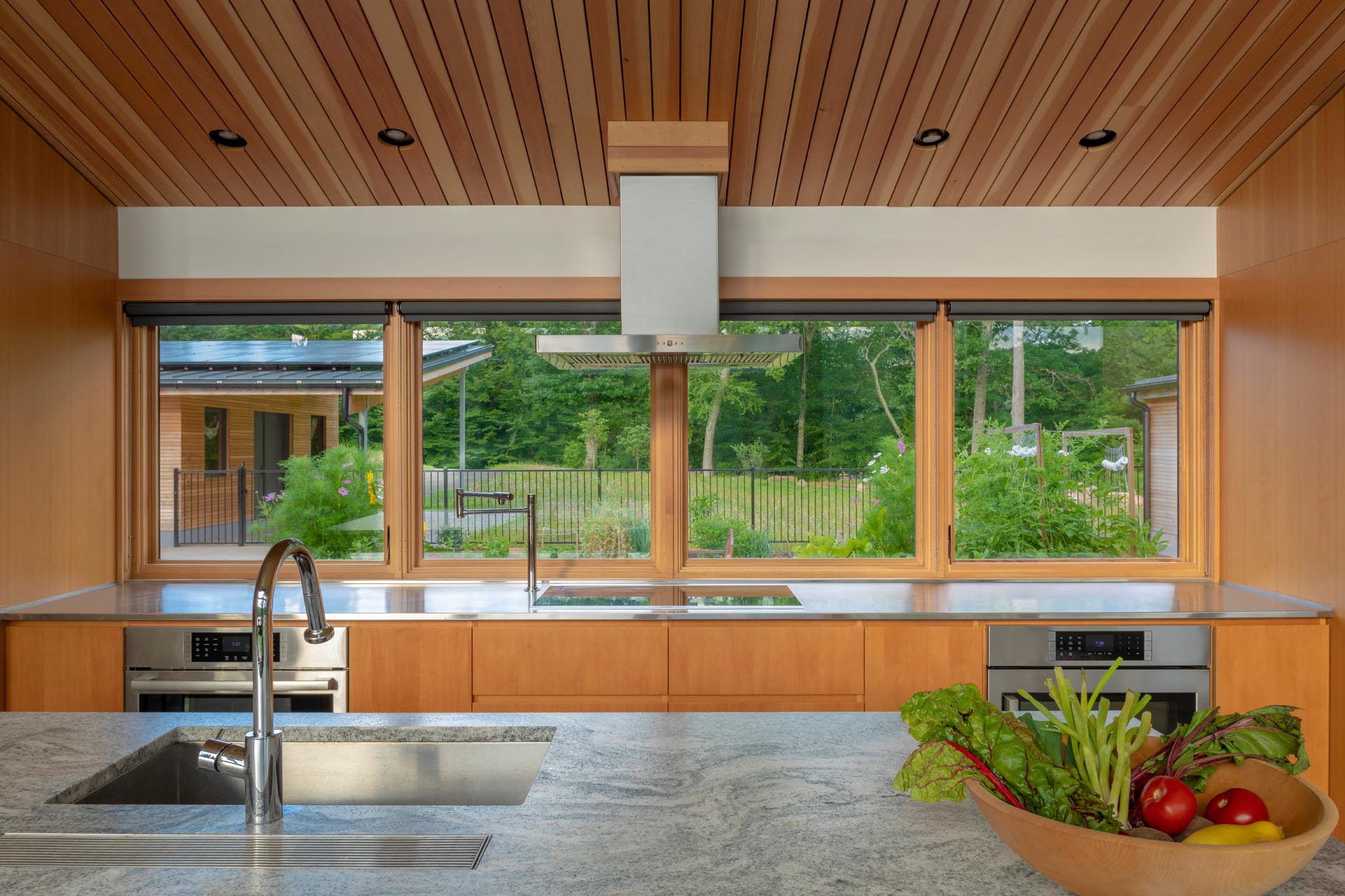 The kitchen has a large island with an undermount stainless steel sink, while windows look out to a courtyard and the workshop.