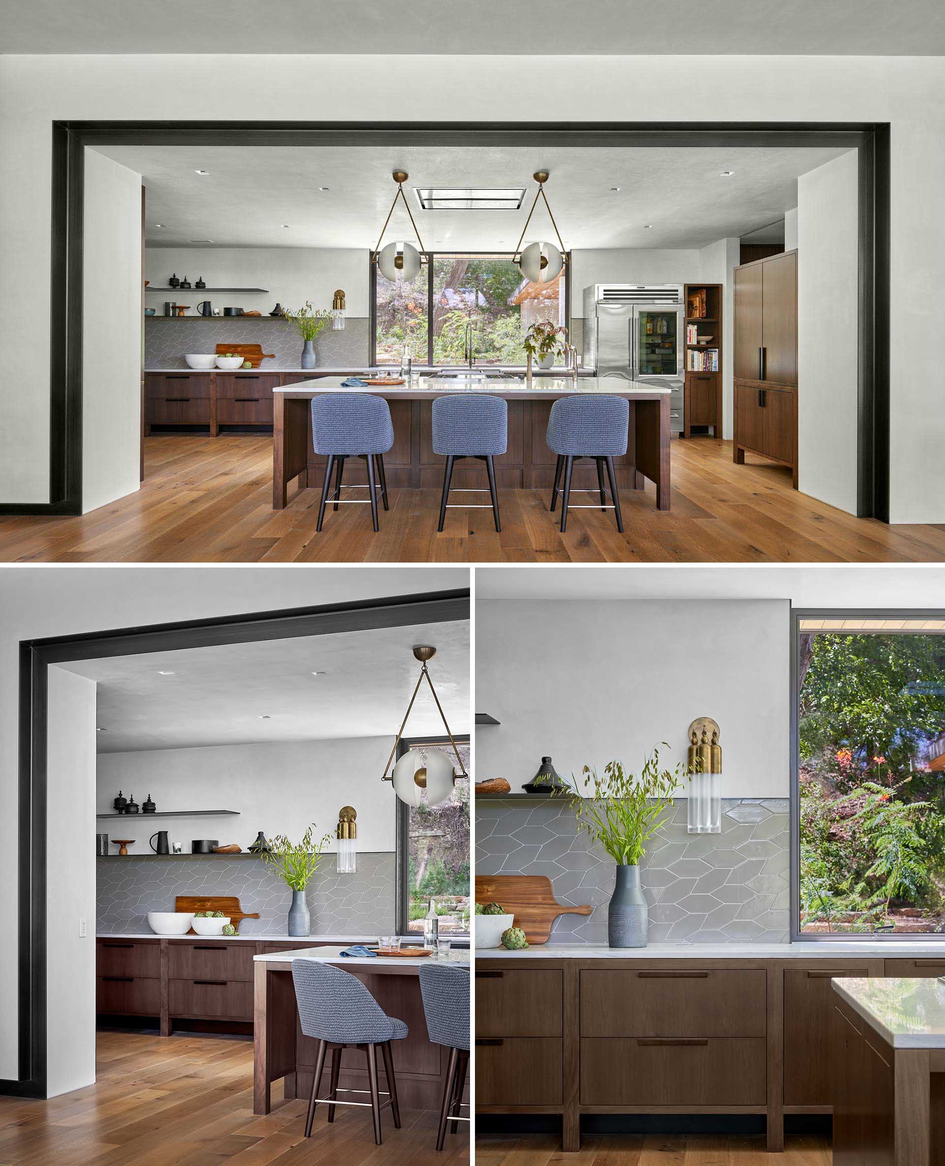 This modern kitchen features cabinets on wooden legs that create a physical and visual space between the floor and cabinets. A glass front refrigerator adds to the design of the kitchen, while a custom kitchen armoire stores coffee making equipment.