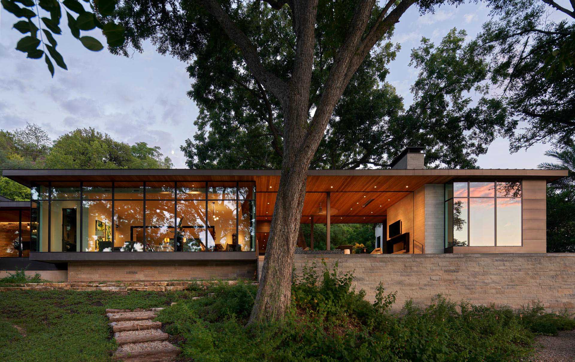 A modern lakeside house with walls of windows and a covered outdoor entertaining space.