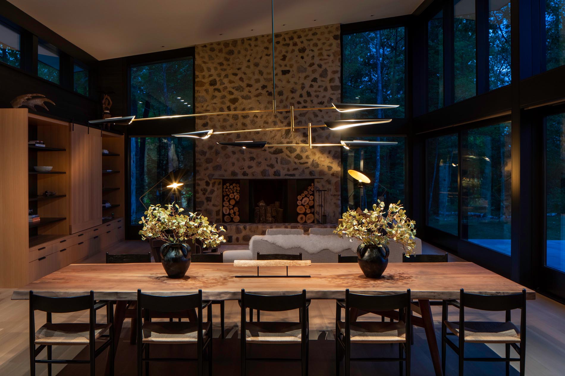 A custom wood dining table by Michael Dreeben and a sculptural David Weeks chandelier separate the living room from the kitchen. The dining area also provides a view of the fireplace that showcases hand-troweled masonry and field stone.