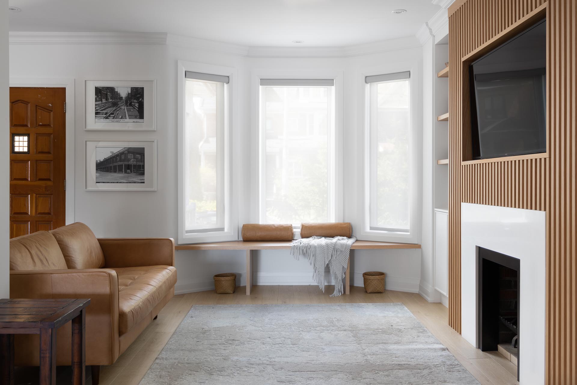 This living room wall has a Scandinavian-inspired design that includes a wood slatted wall that draws the eye, adds a sense of depth, and surrounds the television and fireplace.