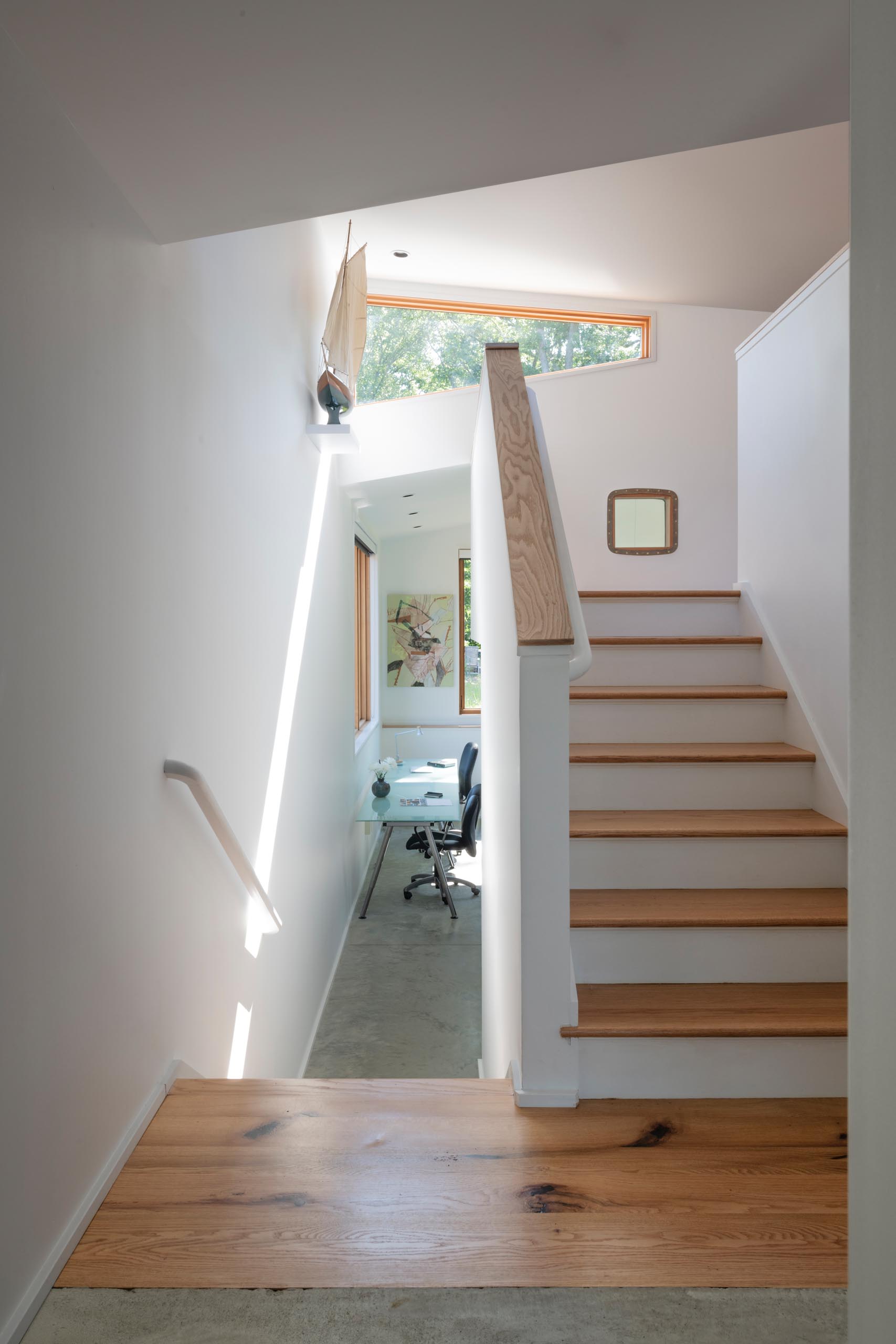 White stairs with wood treads lead to a lofted area in this modern home.