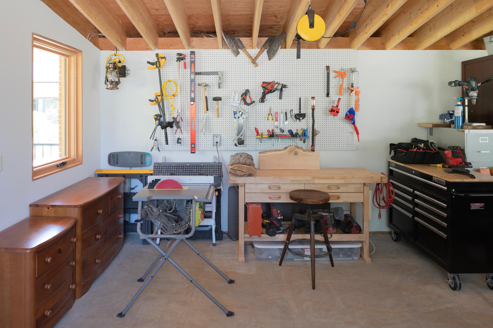 A large garden and carpentry workshop has room for a workbench, furniture and tool storage, and an indoor potting area with a large sink.