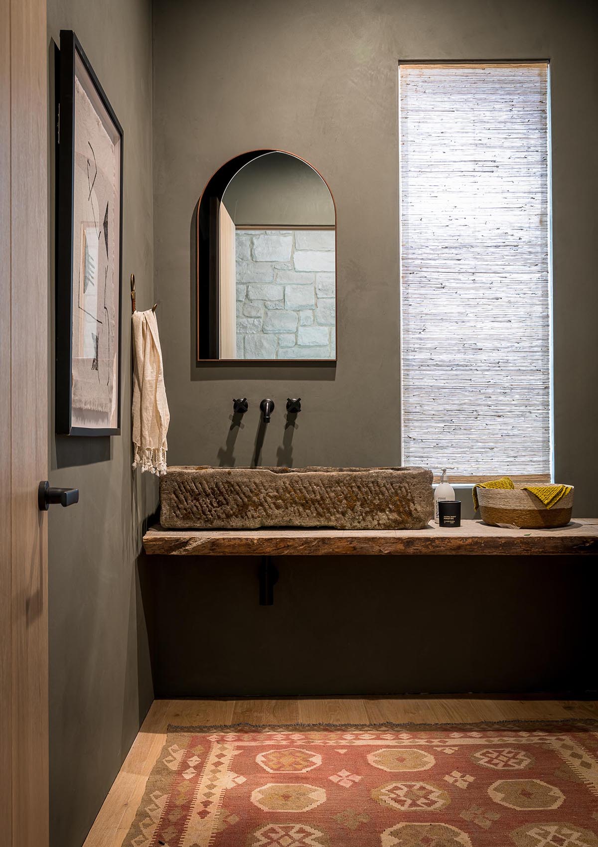 A contemporary farmhouse inspired bathroom with stone sink and live edge wood vanity.