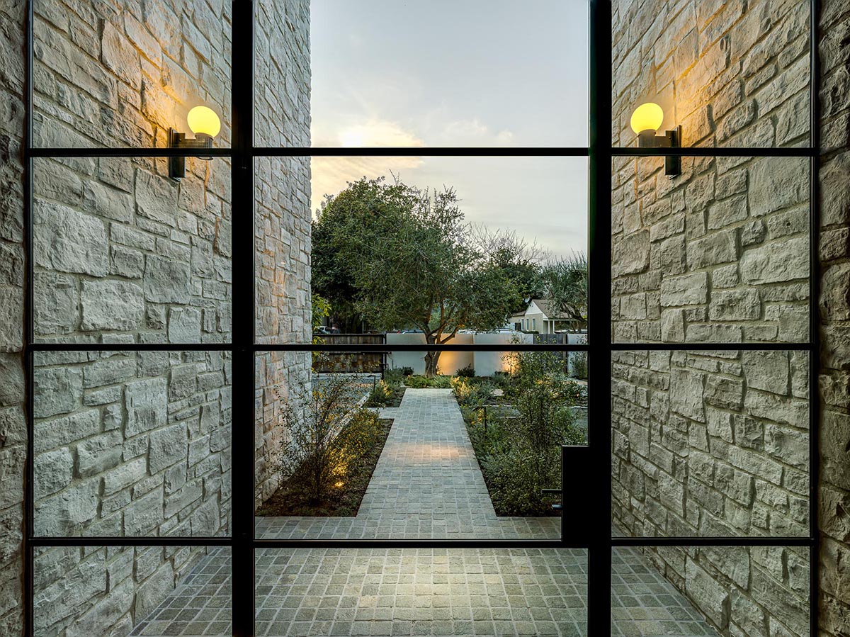 The black-framed glass front door opens to the entryway, where you'll find stone walls, built-in storage, and wide plank white European ¾ oak floors.