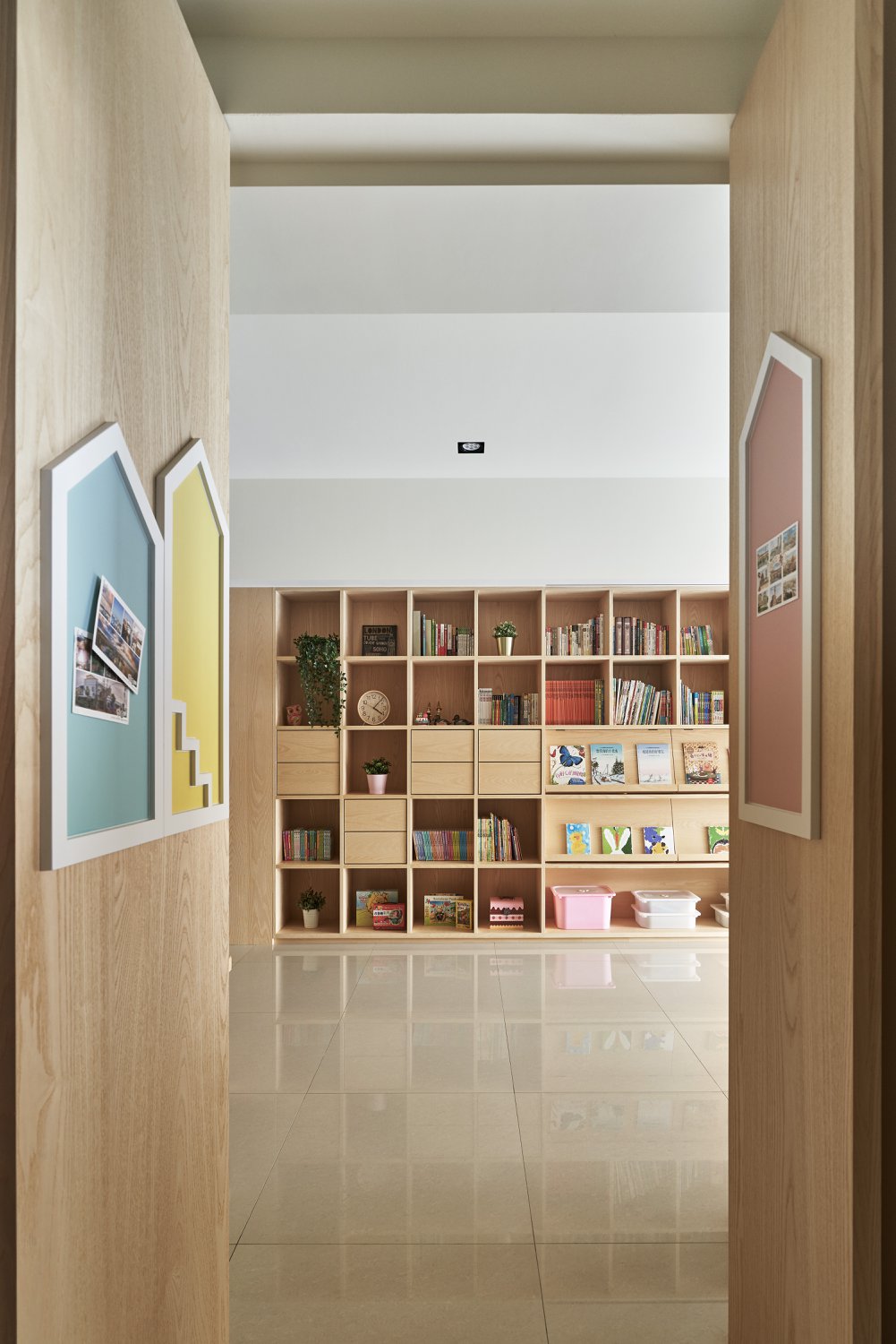 A modern shelving unit with open storage, drawers, book displays, whiteboard walls, and a hidden tv.