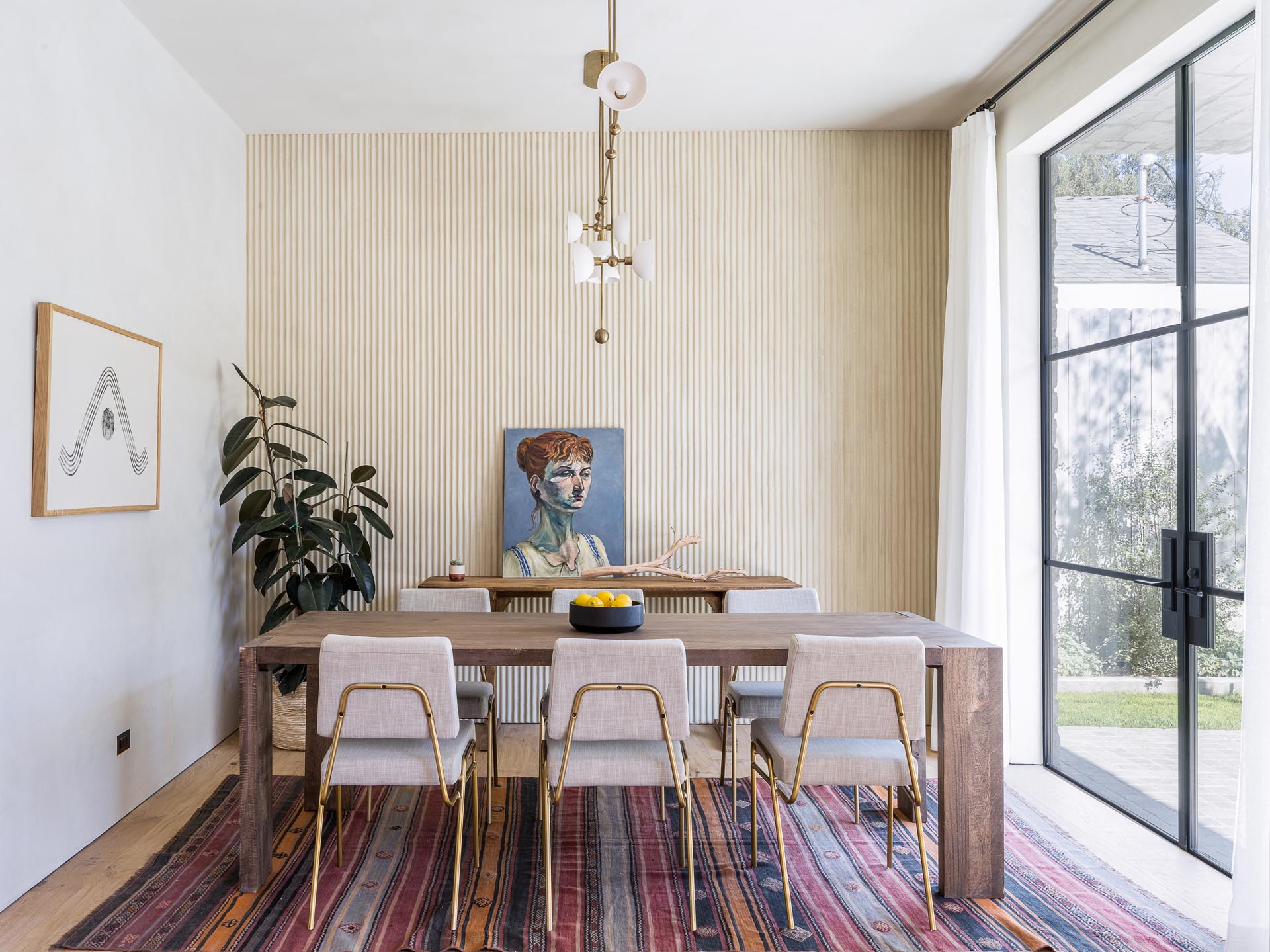 This modern formal dining area showcases a statement plaster wall, while black-framed glass doors open to the backyard.