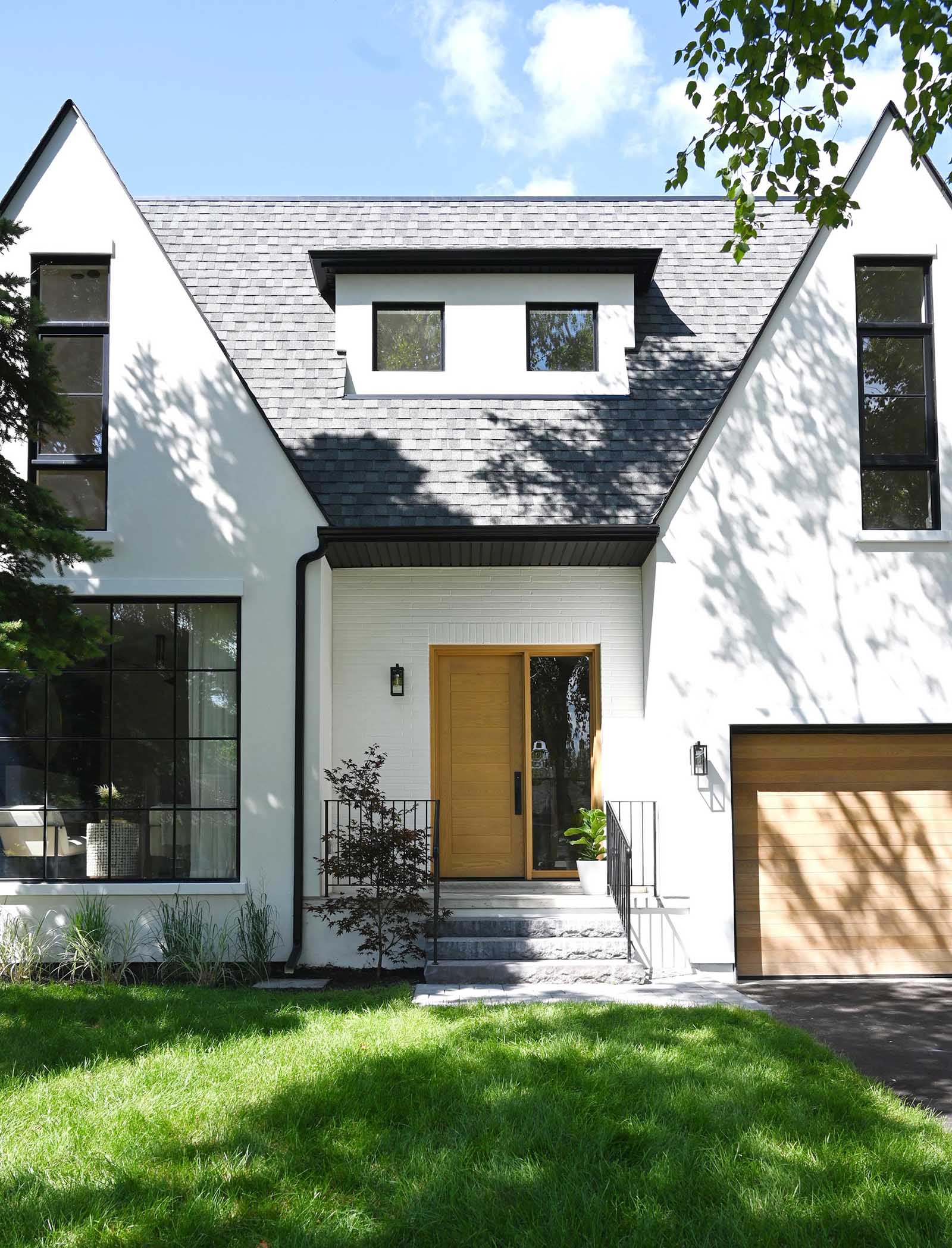 This contemporary home was inspired by farmhouse living, with the white exterior accented by natural white oak wood to add a warm welcome and a hint at what lies beyond.