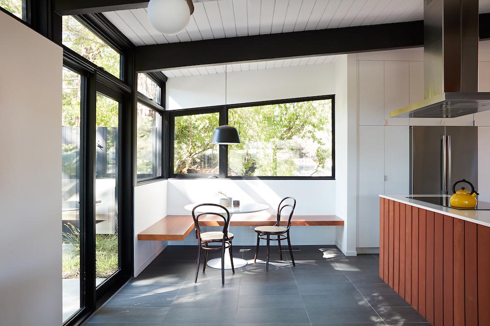 A remodeled kitchen with white cabinets, an open dining area, and a corner breakfast nook.