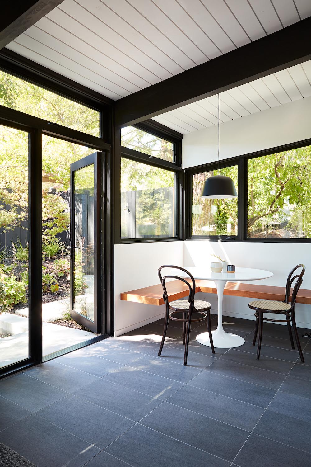 A remodeled kitchen with white cabinets, an open dining area, and a corner breakfast nook.