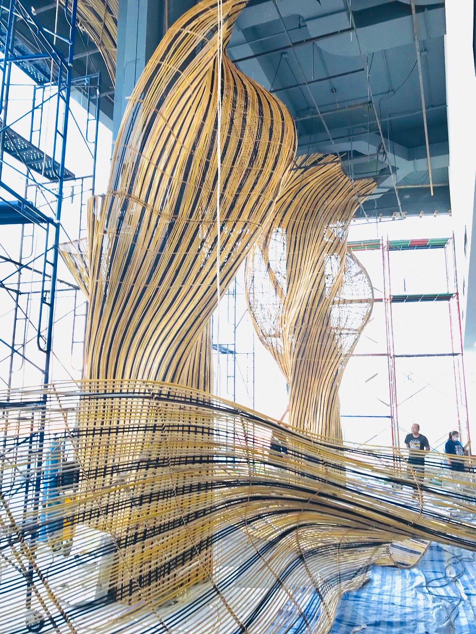 MAKING OF - A modern restaurant with a glass facade that showcases flowing rattan sculptures inside.