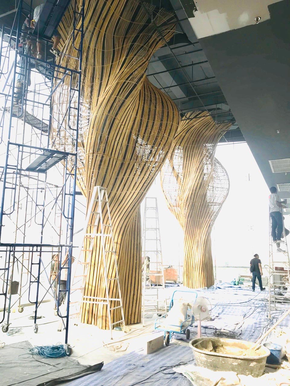 MAKING OF - A modern restaurant with a glass facade that showcases flowing rattan sculptures inside.