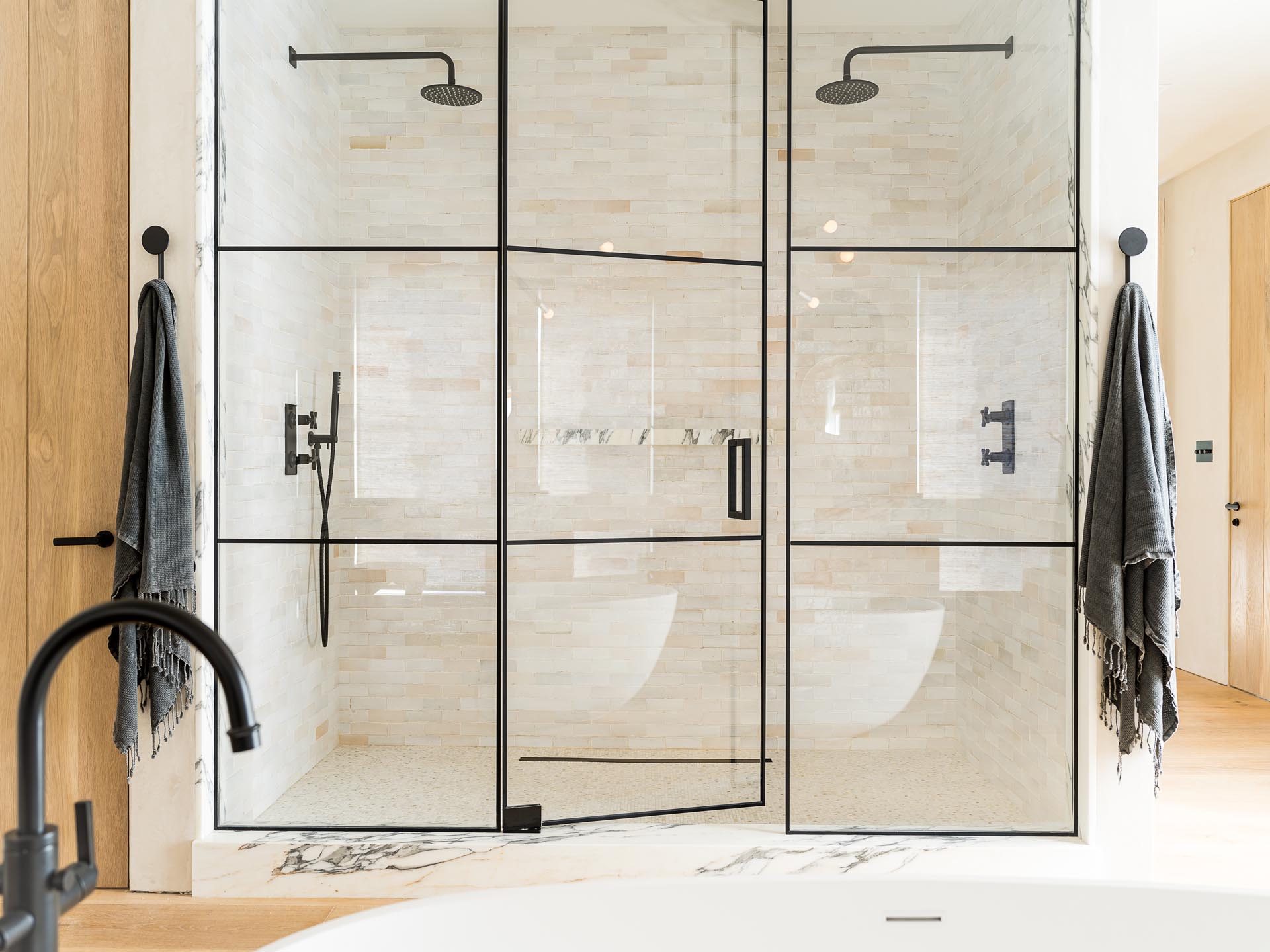 A glass enclosed two person shower with black frames and hardware.