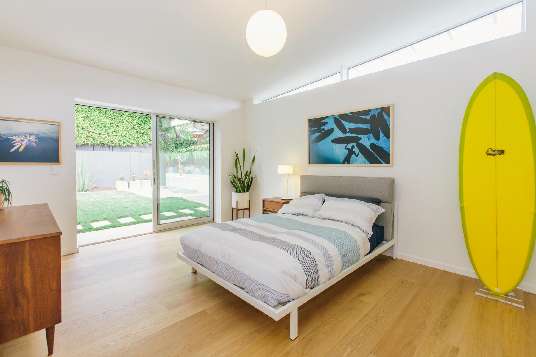 A mid-century modern inspired bedroom has clerestory windows and a sliding door that opens to the yard.