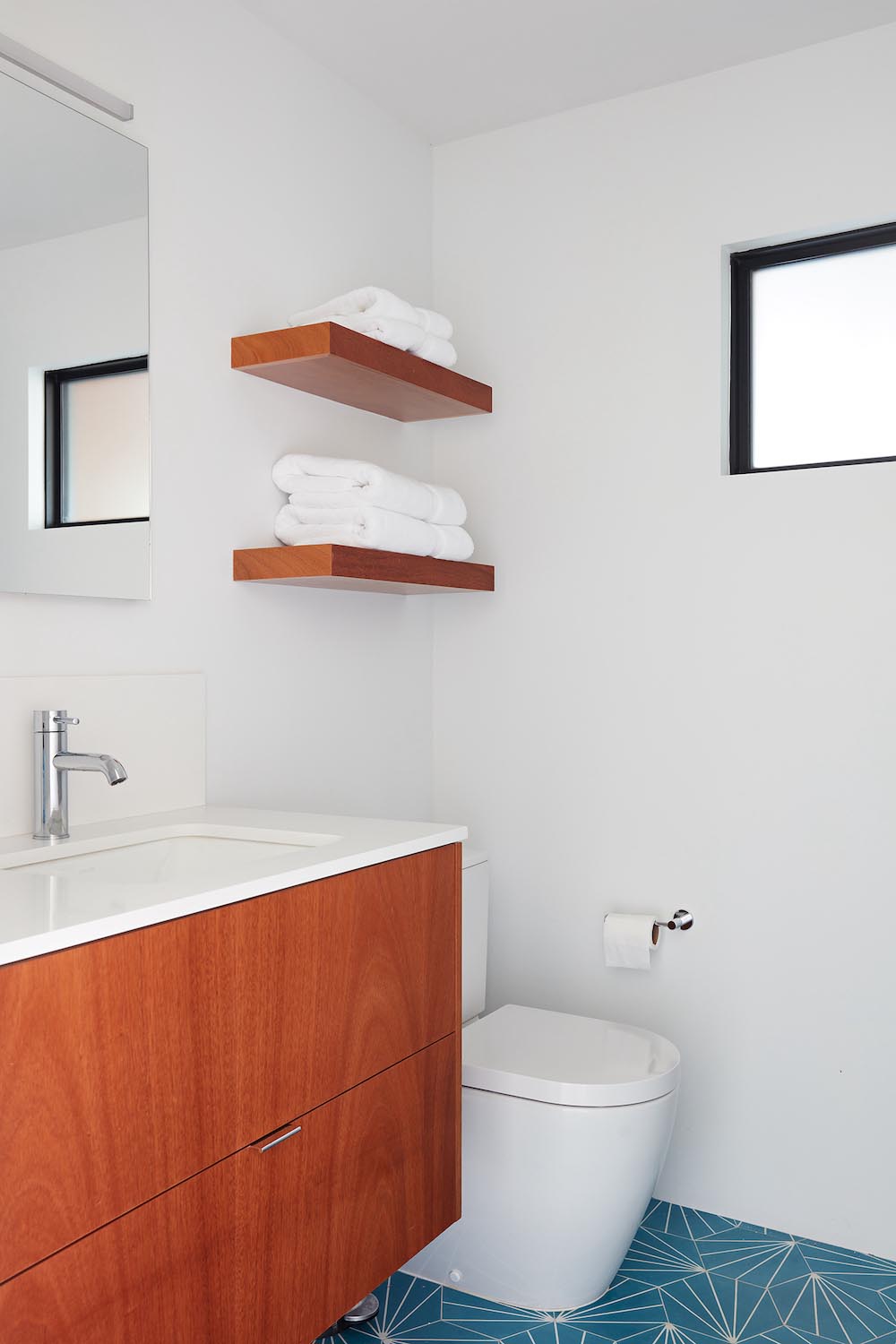 A modern white bathroom with blue starburst tiles and a wood vanity.