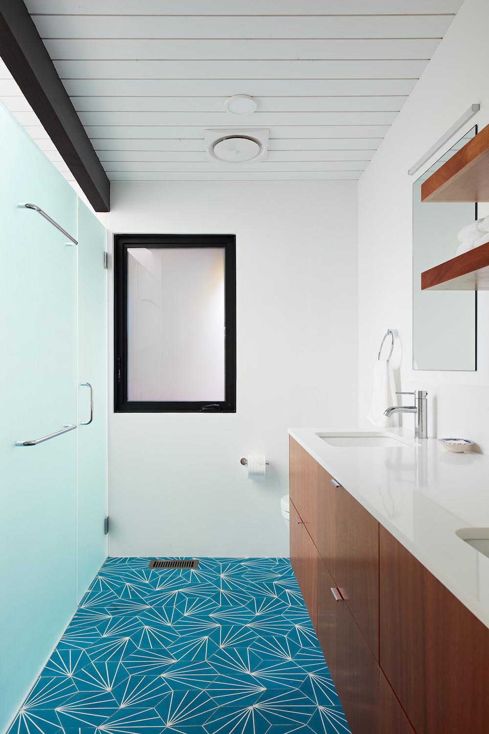 A modern white bathroom with blue starburst tiles and a wood vanity.
