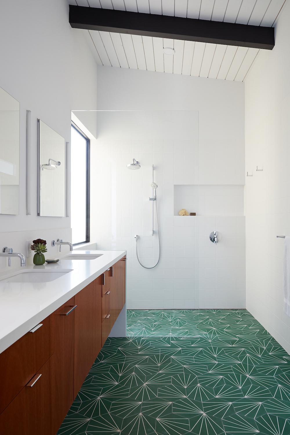 A modern white bathroom with green starburst tiles and a wood vanity.