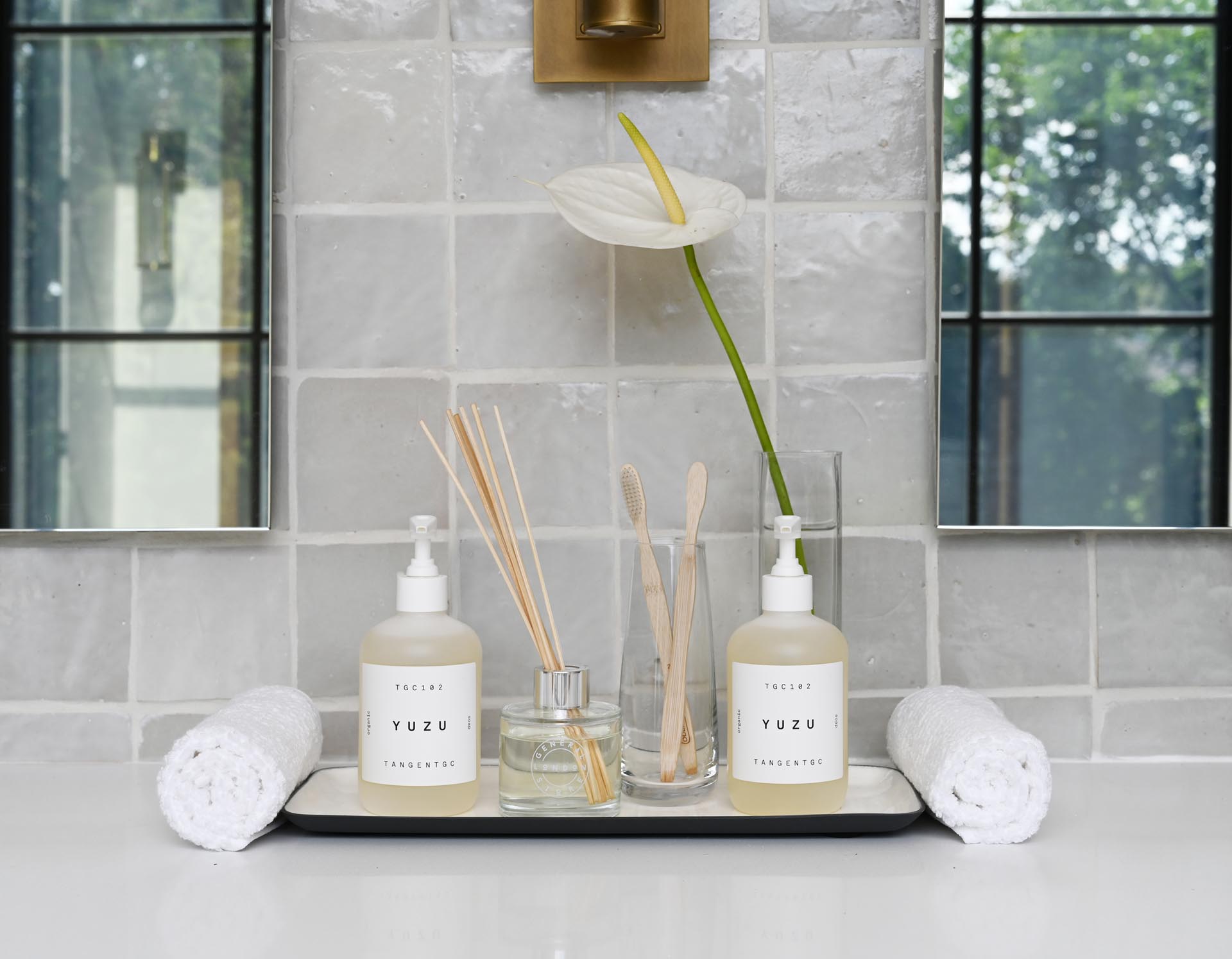 This modern white marbled spa-like bathroom includes a windowed alcove for the freestanding tub, metallic hardware, and wood accents.