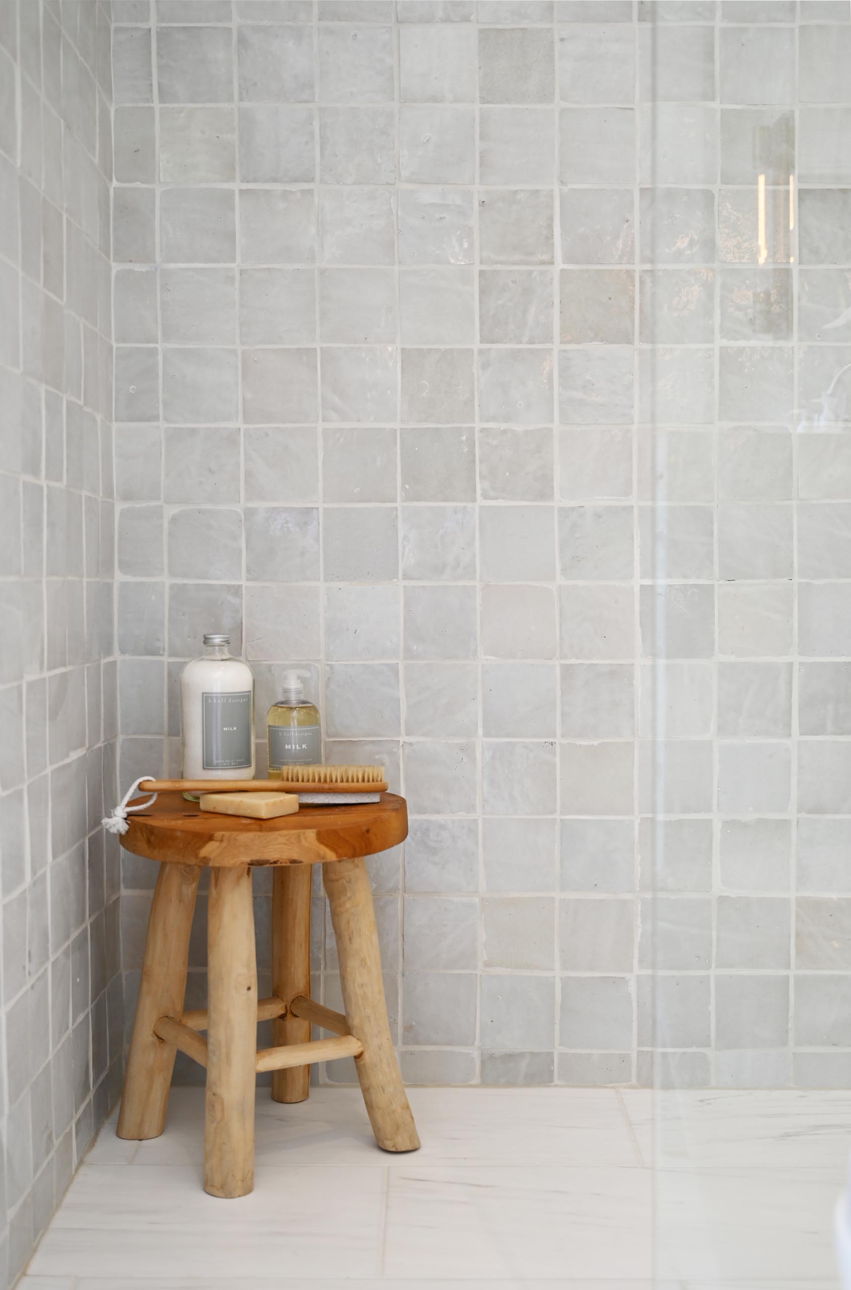 Phòng tắm giống spa lát đá cẩm thạch trắng hiện đại này có hốc tường có cửa sổ cho bồn tắm đứng, phần cứng bằng kim loại và các điểm nhấn bằng gỗ.