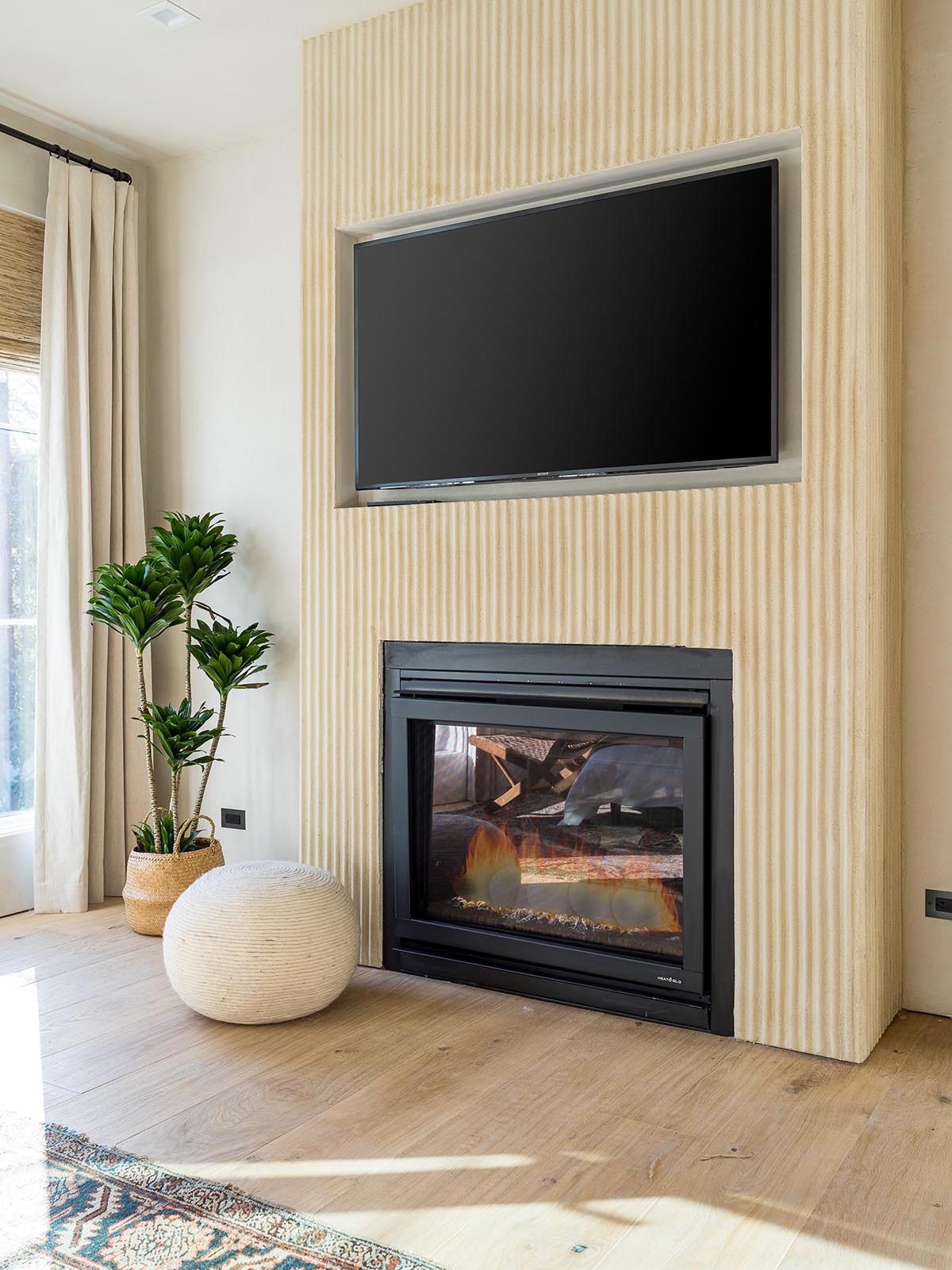 The primary bedroom has textured accents walls, as well as a fireplace and recessed television.