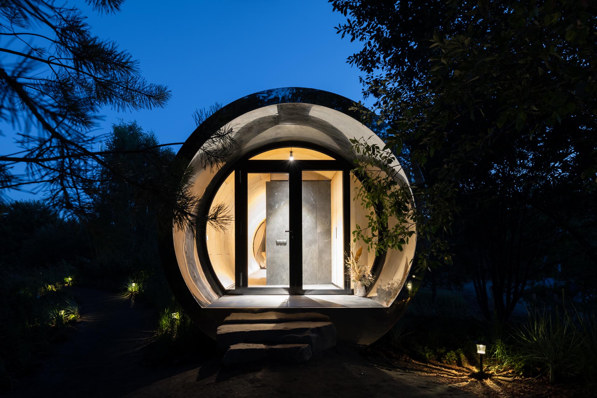 A unique tube-inspired cabin with a stainless steel exterior and a wood-lined interior.