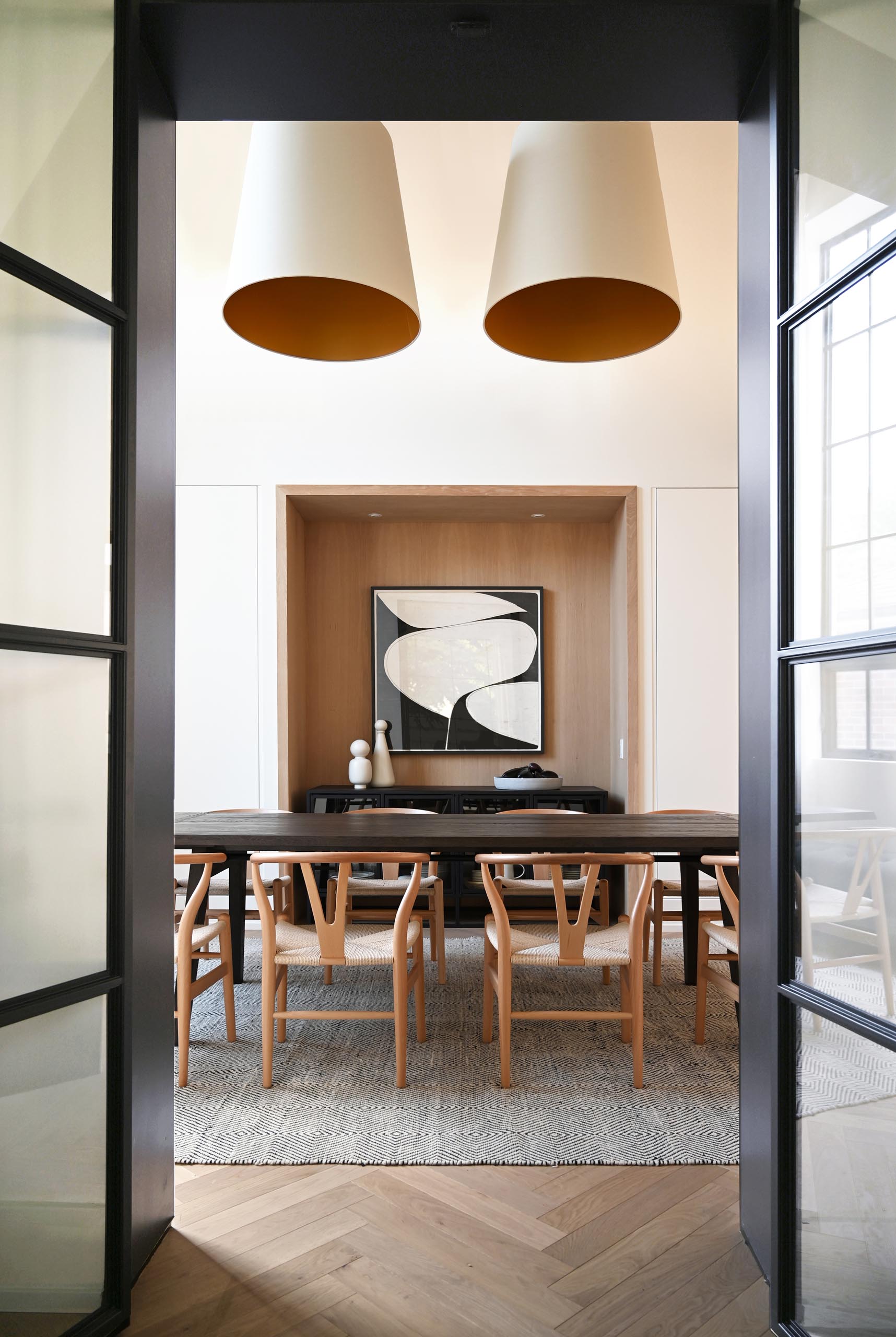 This farmhouse-inspired kitchen and dining room feature cathedral ceilings with exposed wood beams, warm wood accents and natural materials. Oversized pendant lights complement the grand space, and add a warm glow for evenings spent around the large dining table.