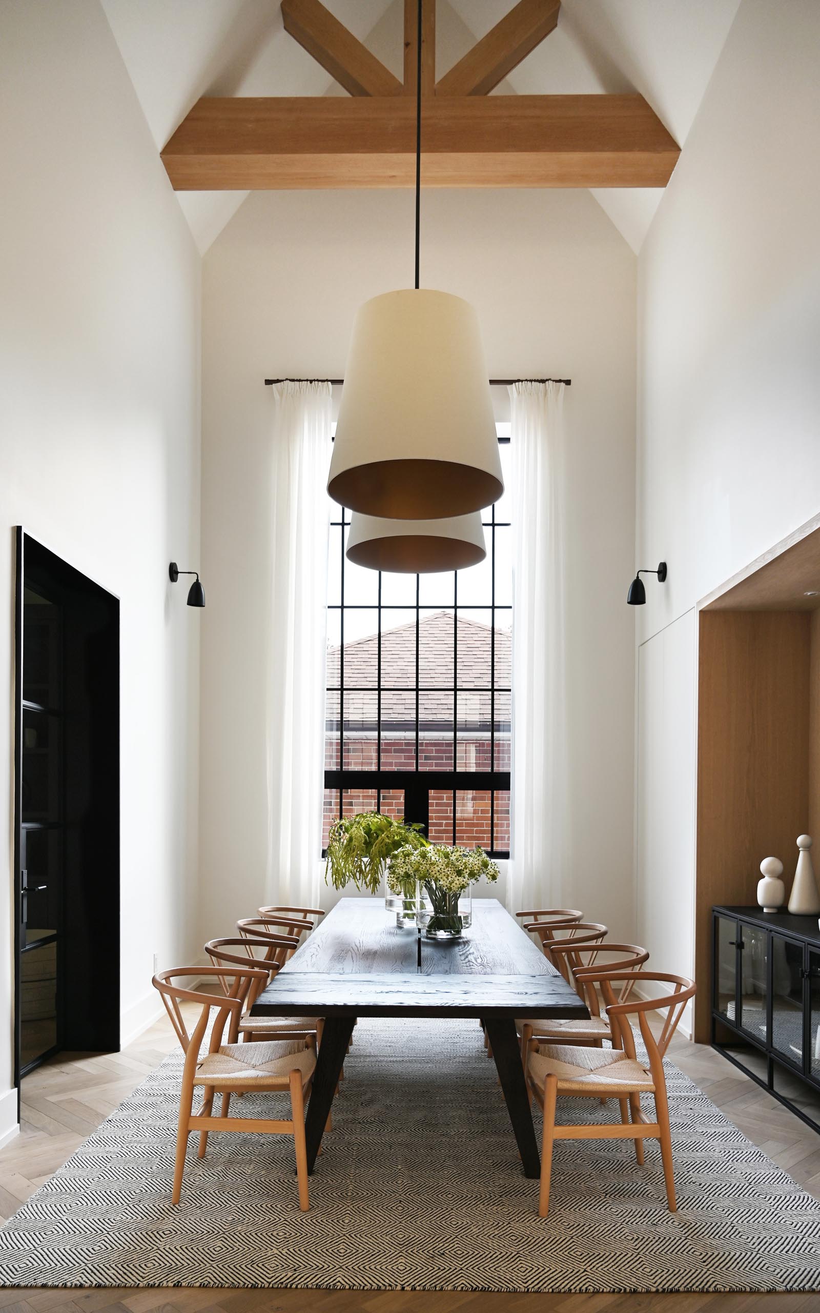 This farmhouse-inspired kitchen and dining room feature cathedral ceilings with exposed wood beams, warm wood accents and natural materials. Oversized pendant lights complement the grand space, and add a warm glow for evenings spent around the large dining table.