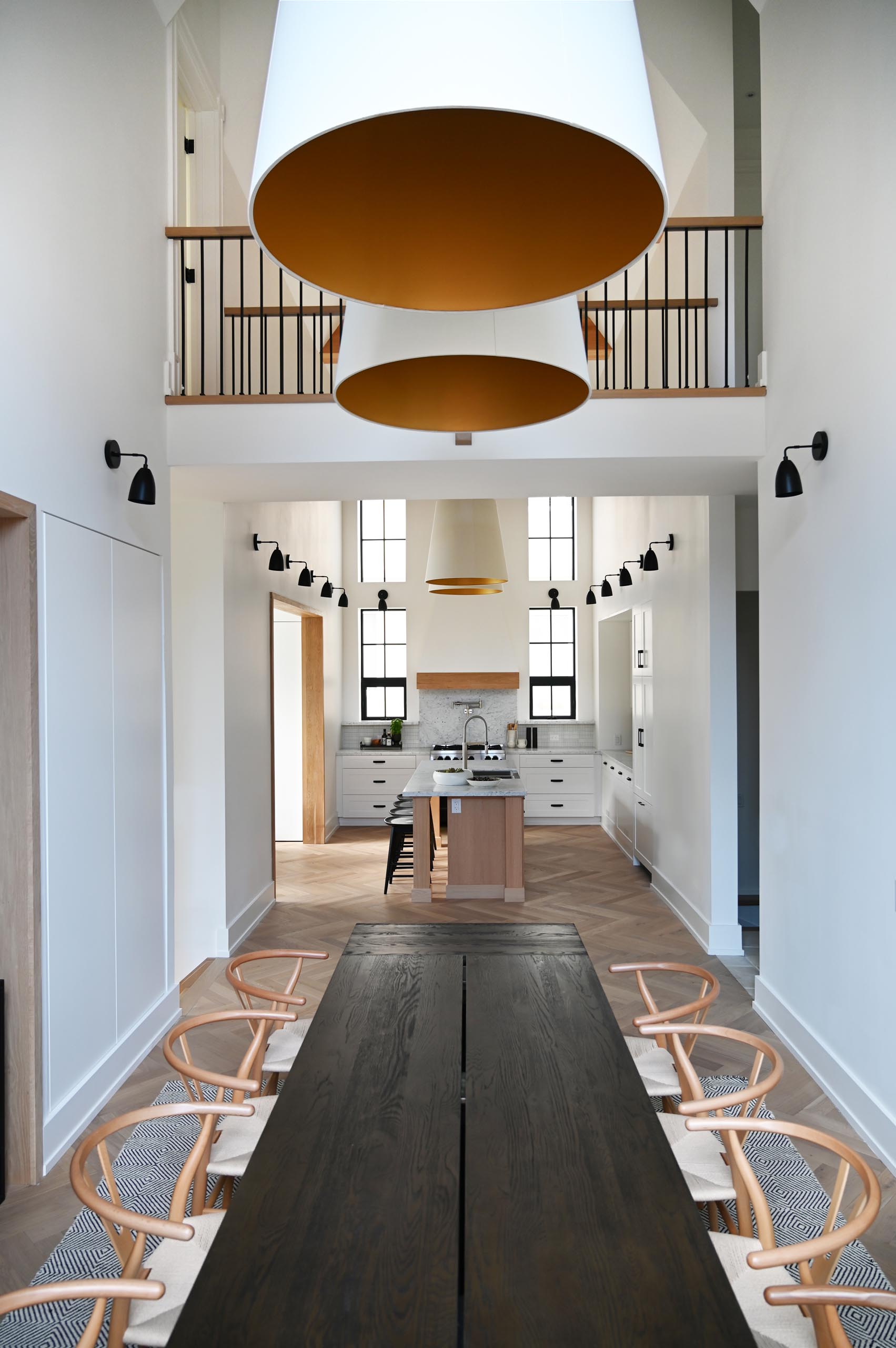 This farmhouse-inspired kitchen and dining room feature cathedral ceilings with exposed wood beams, warm wood accents and natural materials. Oversized pendant lights complement the grand space, and add a warm glow for evenings spent around the large dining table.