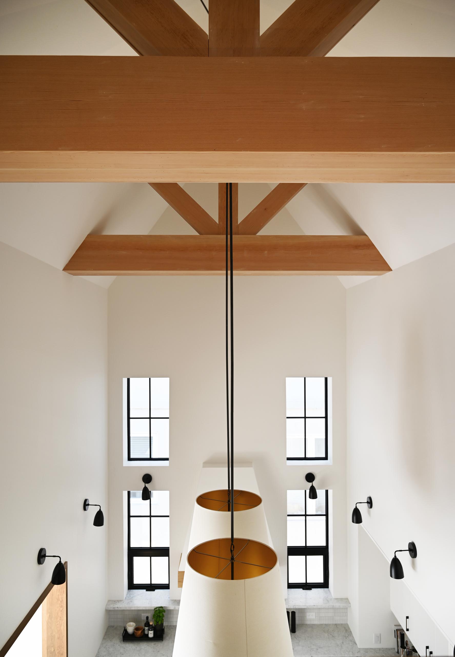 This farmhouse-inspired kitchen and dining room feature cathedral ceilings with exposed wood beams, warm wood accents and natural materials. Oversized pendant lights complement the grand space, and add a warm glow for evenings spent around the large dining table.