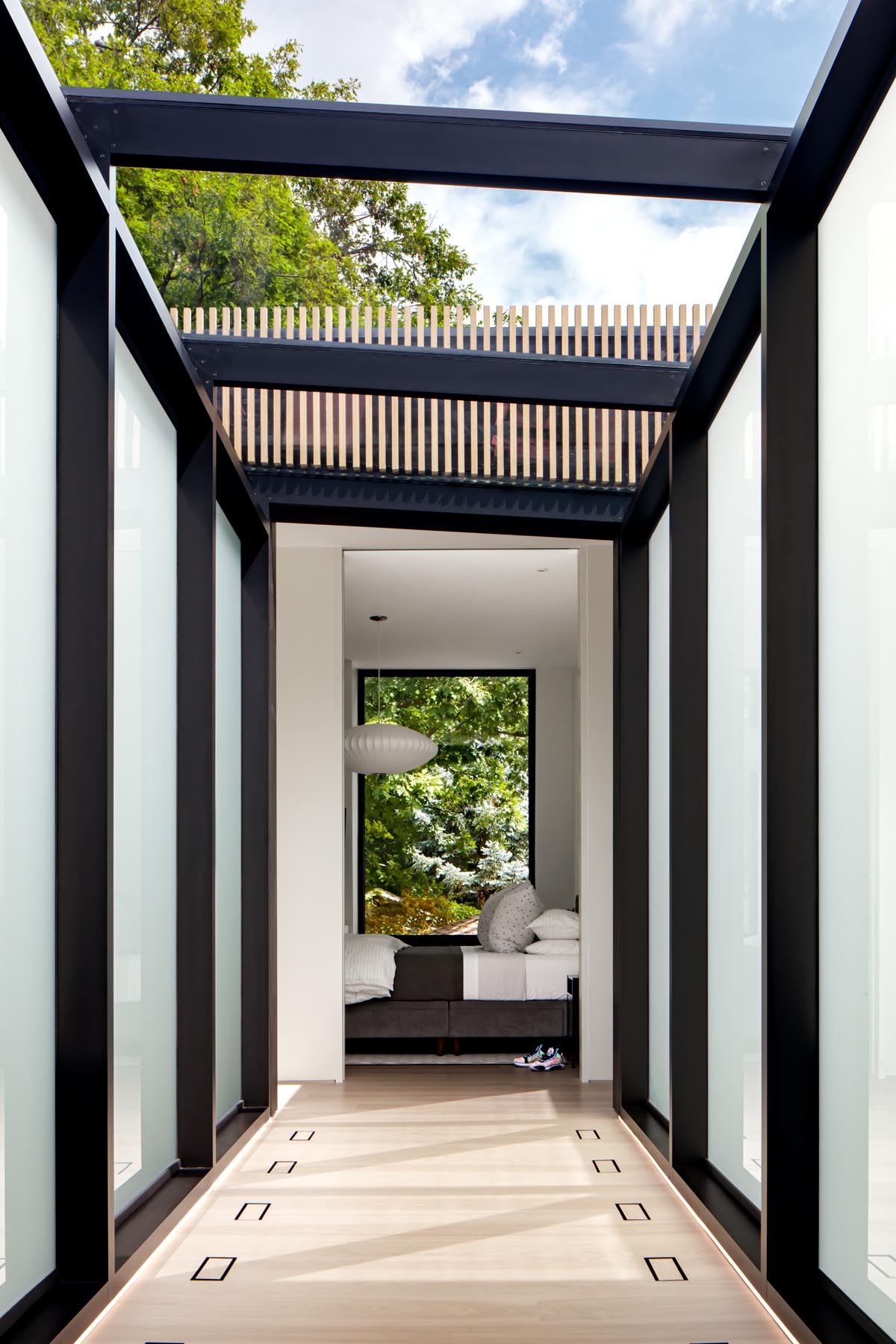 A hallway with a glass ceiling connects the top of the stairs to the bedrooms.