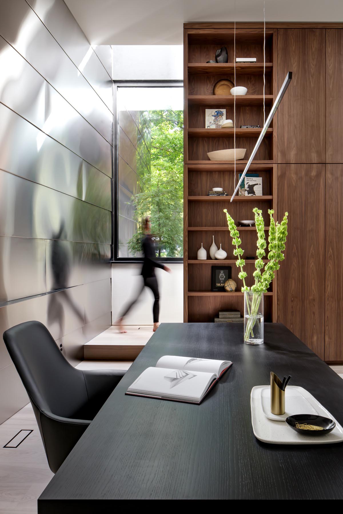 An open plan home office with walnut shelving.