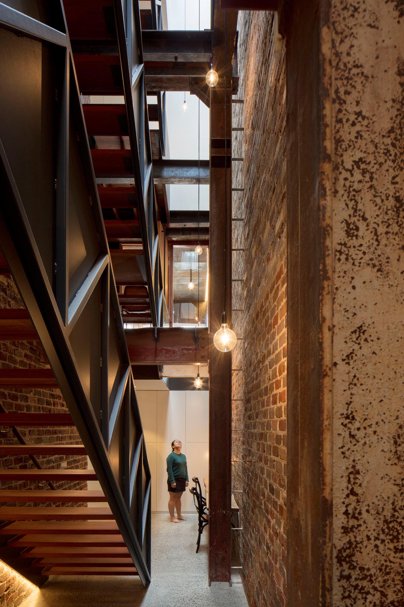 Stepping inside this home, and you're immediately greeted by a recycled three storey brick wall that follows the staircase up, and compliments the steel beam elements on display throughout the home.