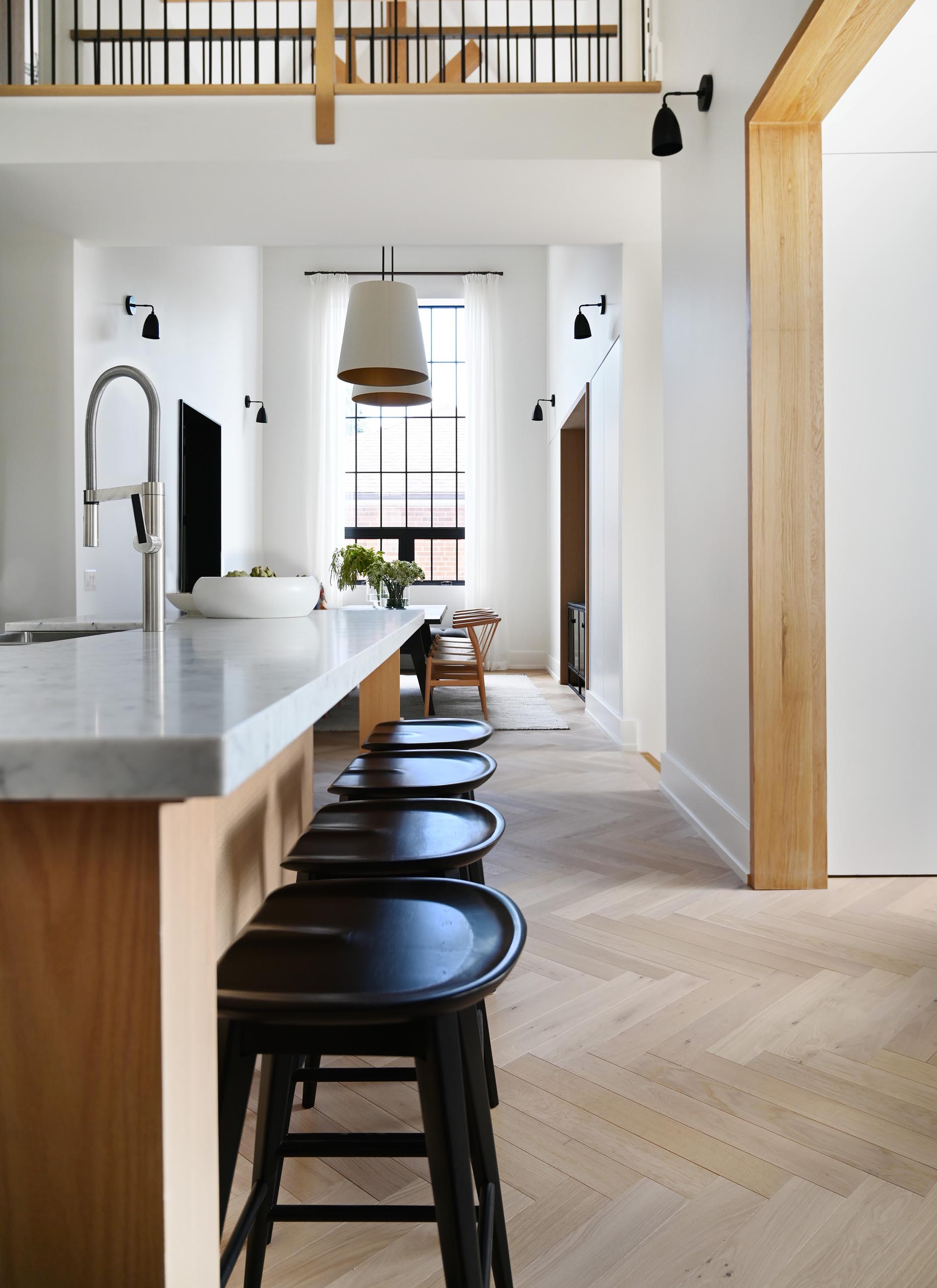 This farmhouse-inspired kitchen and dining room feature cathedral ceilings with exposed wood beams, warm wood accents and natural materials. Oversized pendant lights complement the grand space, and add a warm glow for evenings spent around the large dining table.