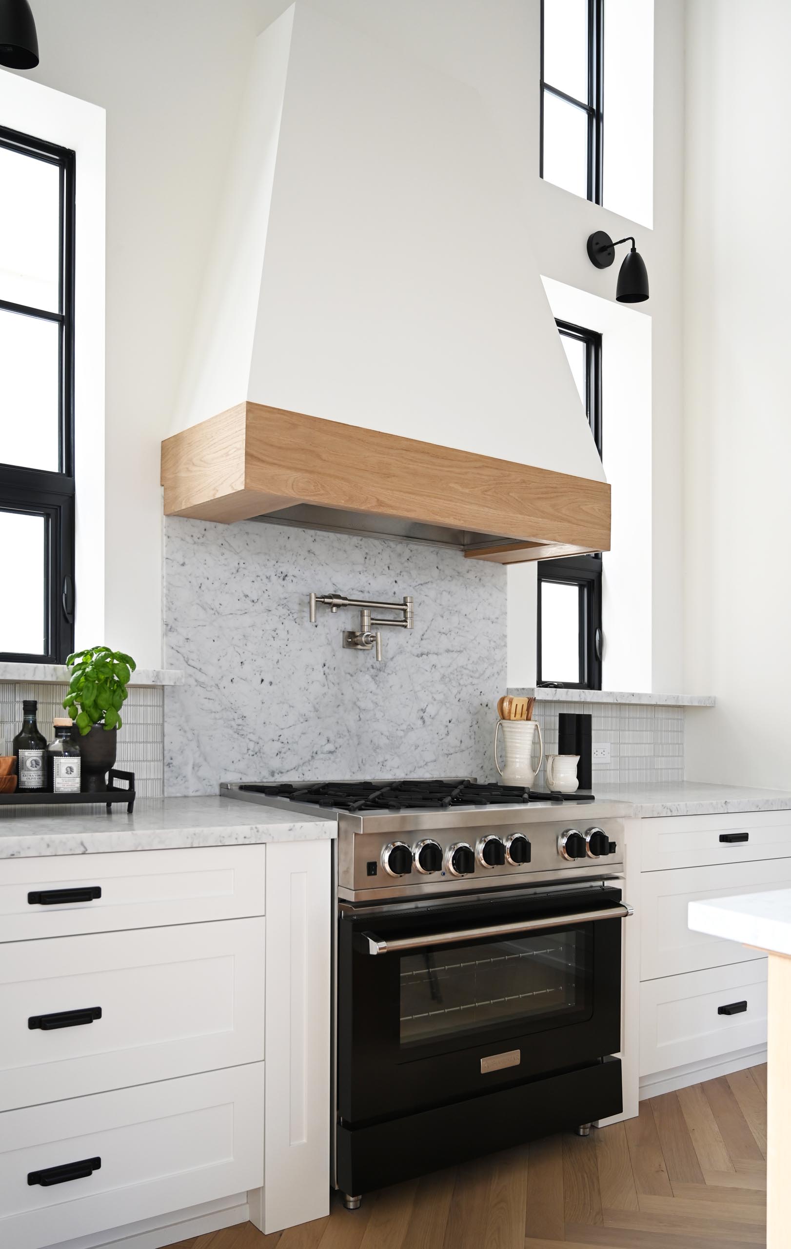 A contemporary farmhouse-inspired kitchen with gray countertops, white cabinets, and wood accents.