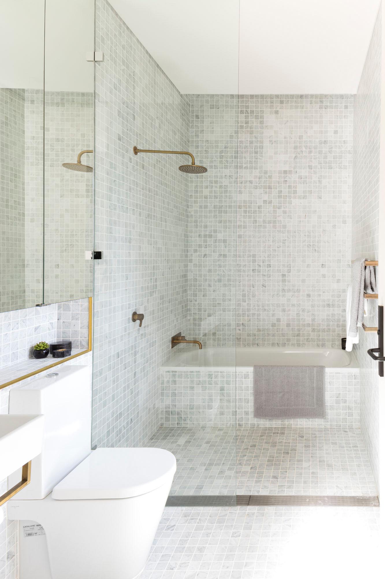 A modern bathroom with small square gray tiles and brass fixtures.