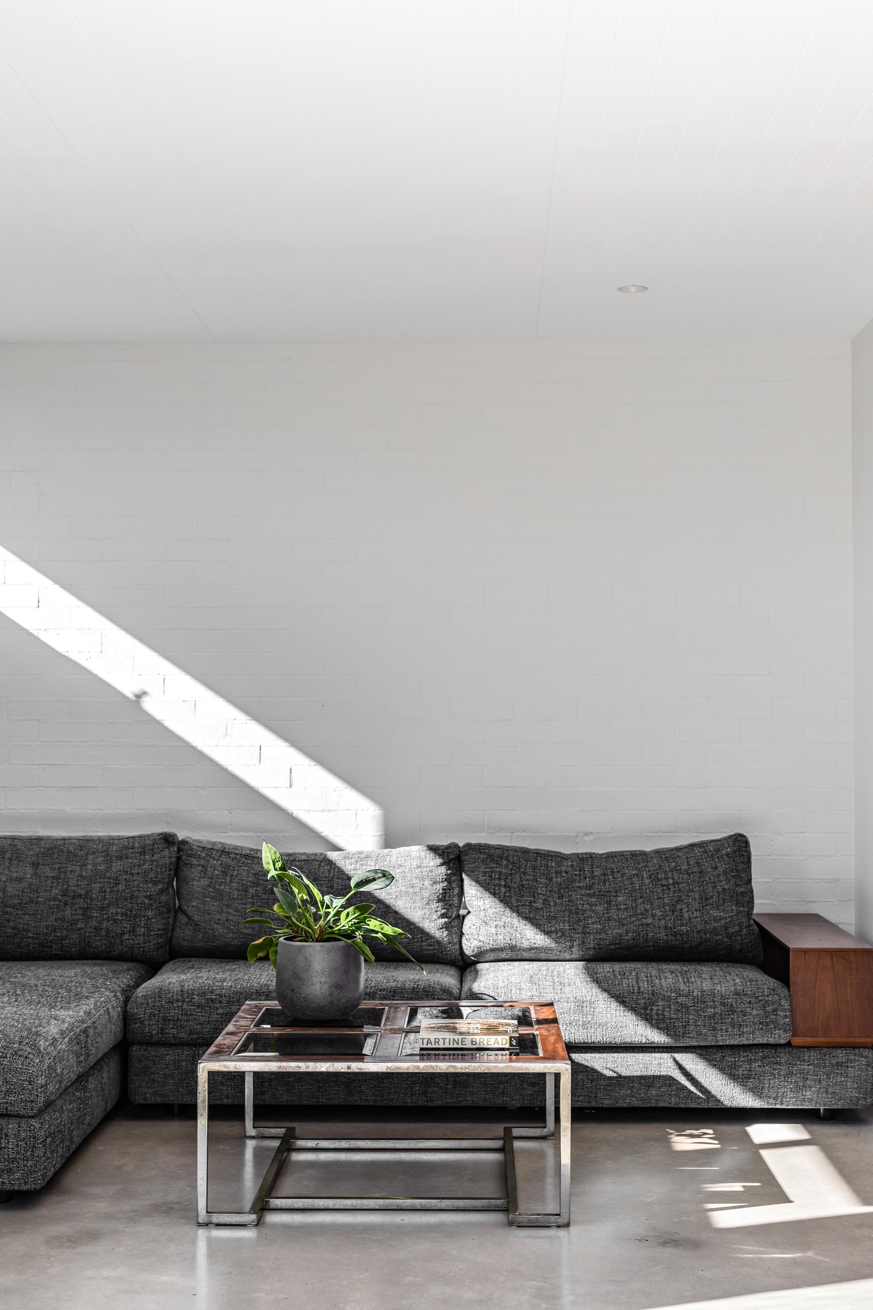 A textured white wall provides a backdrop for the gray couch with wood accents.