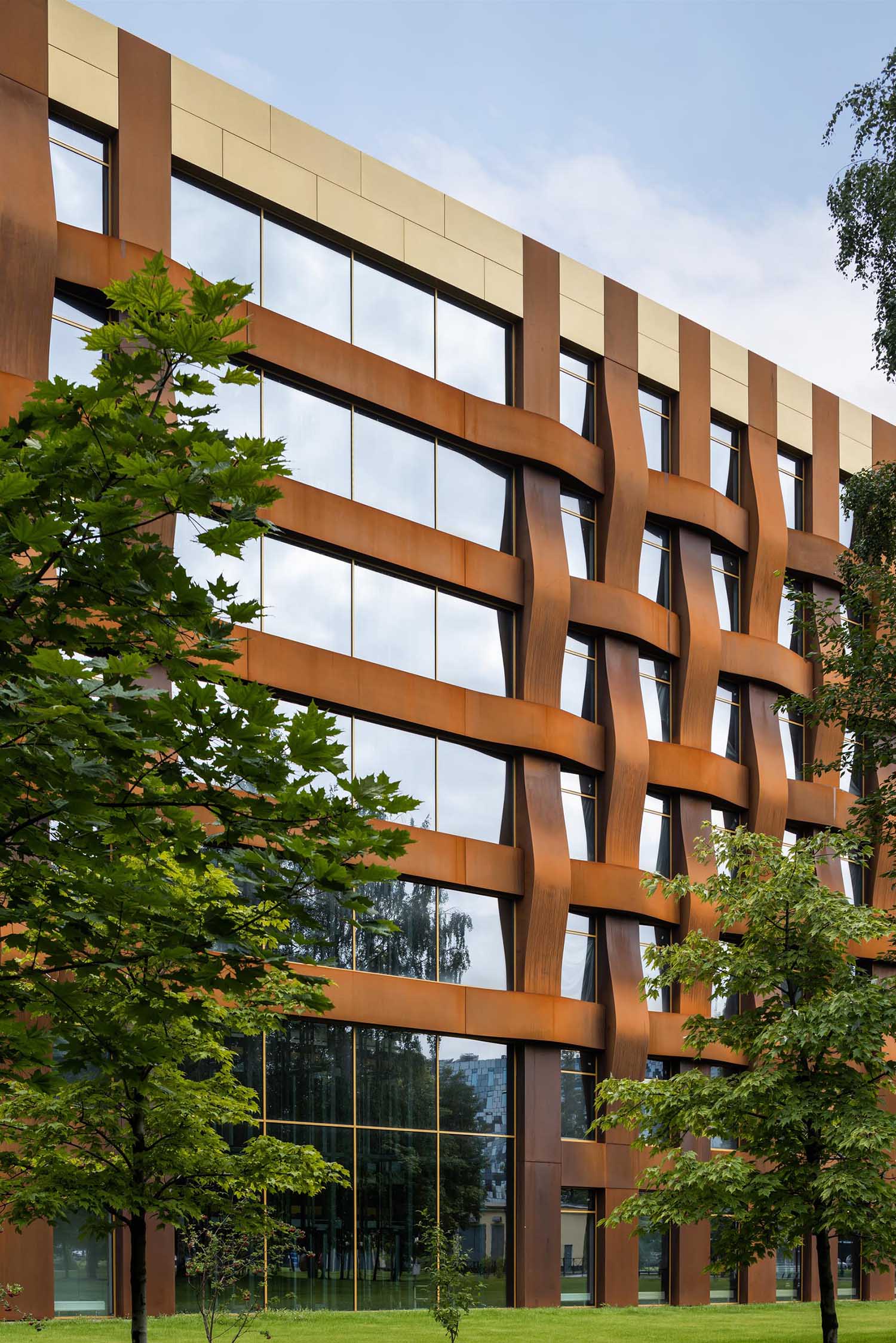 The sculptural weathered steel facade of this modern office building is constructed in a geometric grid and presents itself as a dynamic, organically flowing fabric of loose "warp and weft" threads.