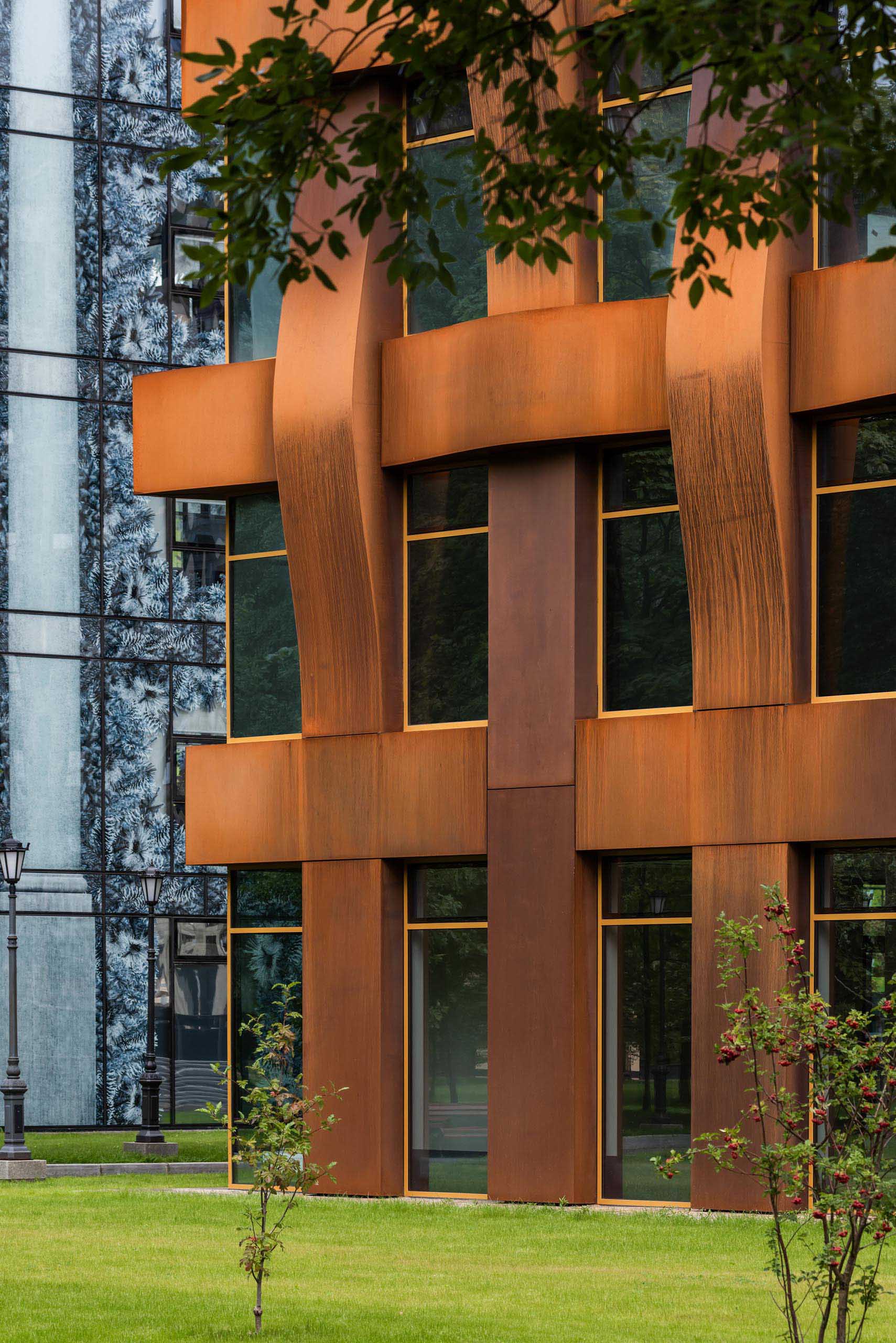 The sculptural weathered steel facade of this modern office building is constructed in a geometric grid and presents itself as a dynamic, organically flowing fabric of loose "warp and weft" threads.